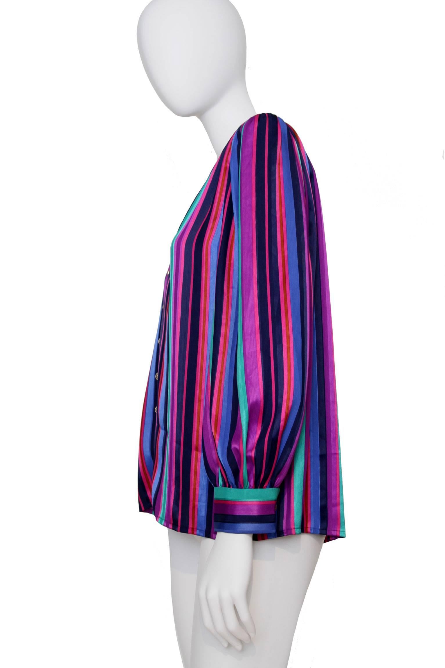 A multicolored 1980s Yves Saint Laurent striped silk shirt with one buttoned cuff and structured shoulders. The vertical stripes are held in various colors and vary in size following a color scheme of black, purple, green, blue and red. The