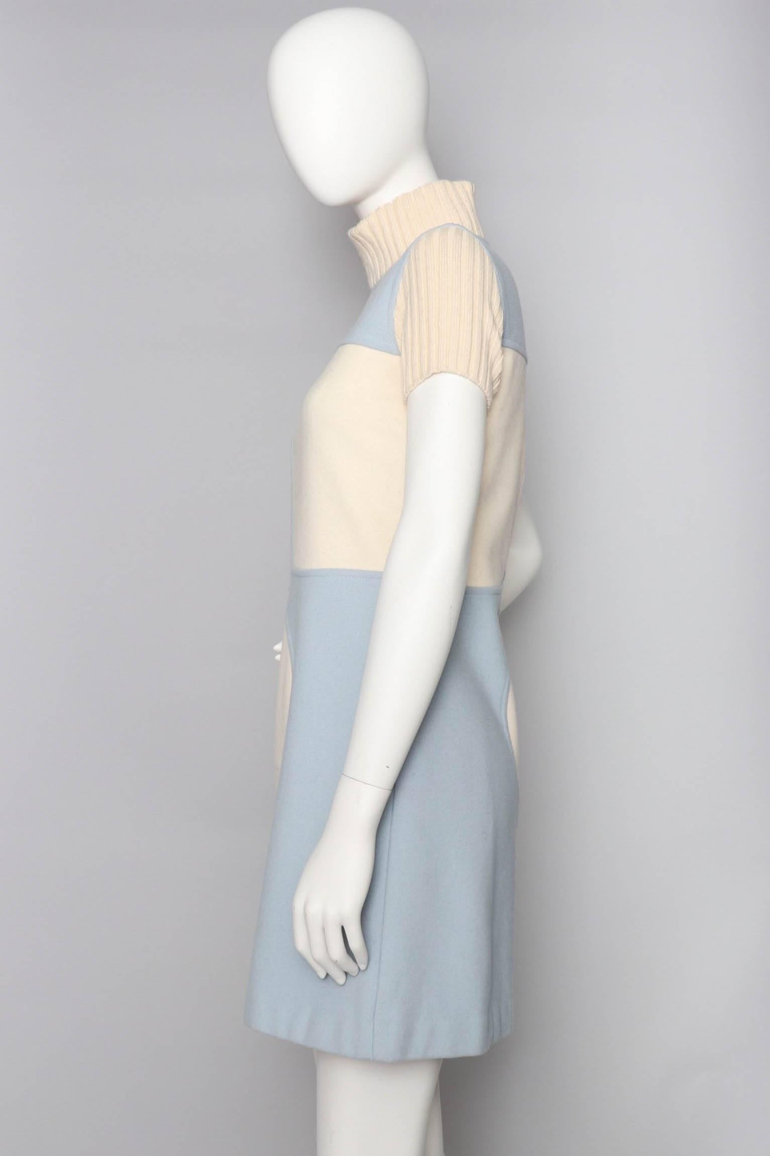 A fabulous 1960s light blue Courrèges wool mini dress with a high rib knit collar and short rib knit sleeves. Two white rounded panels are placed across the bust and hip area, while a small white logo is placed in the centre front of the dress. The