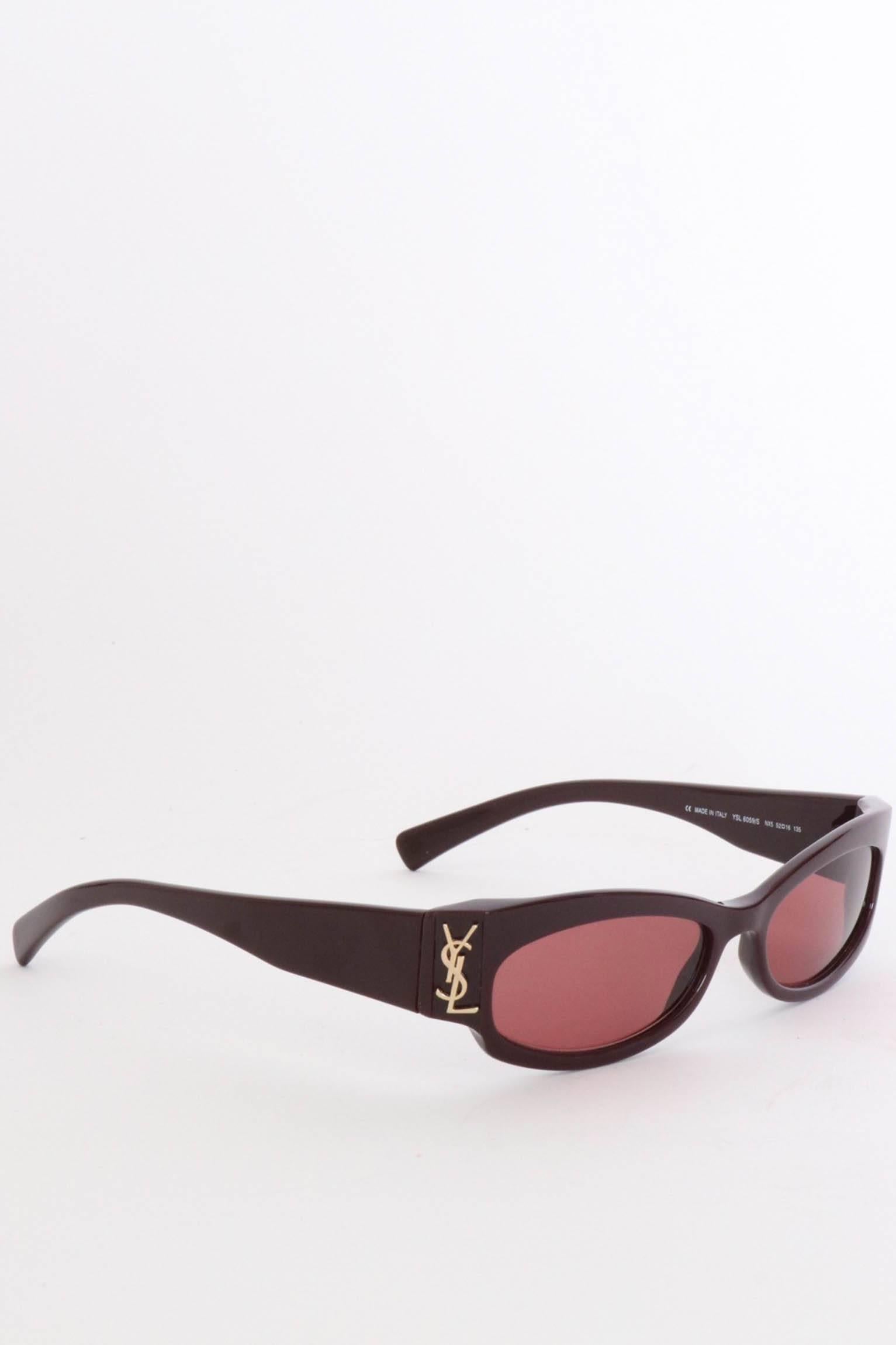 A pair of 1990s Yves Saint Laurent bordeaux sunglasses with a slim frame, red tinted glasses and a gold colored YSL logo situated on both sides of the front. 

The glasses measure: 
Temple length: 13 cm 
Bridge size: 1 cm 
Eye size: 6 cm

