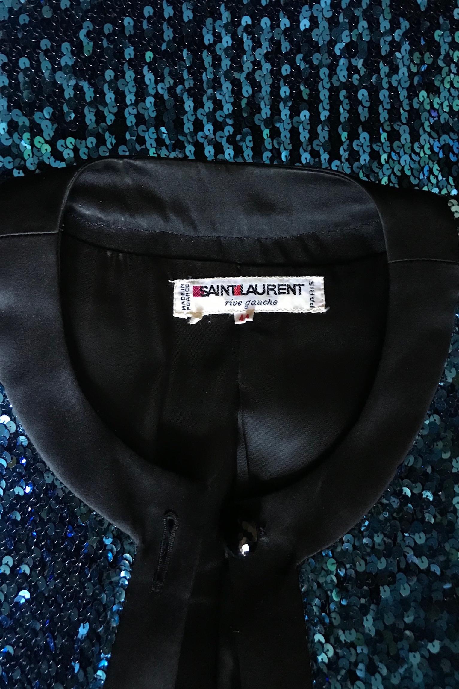An absolutely fabulous 1980s Yves Saint Laurent Rive Gauche blue sequined skirt suit consisting of a fitted jacket and pencil skirt. 

The jacket has long tapered sleeves, shoulder-pads, a front buttoned closure and black trim around the cuffs,