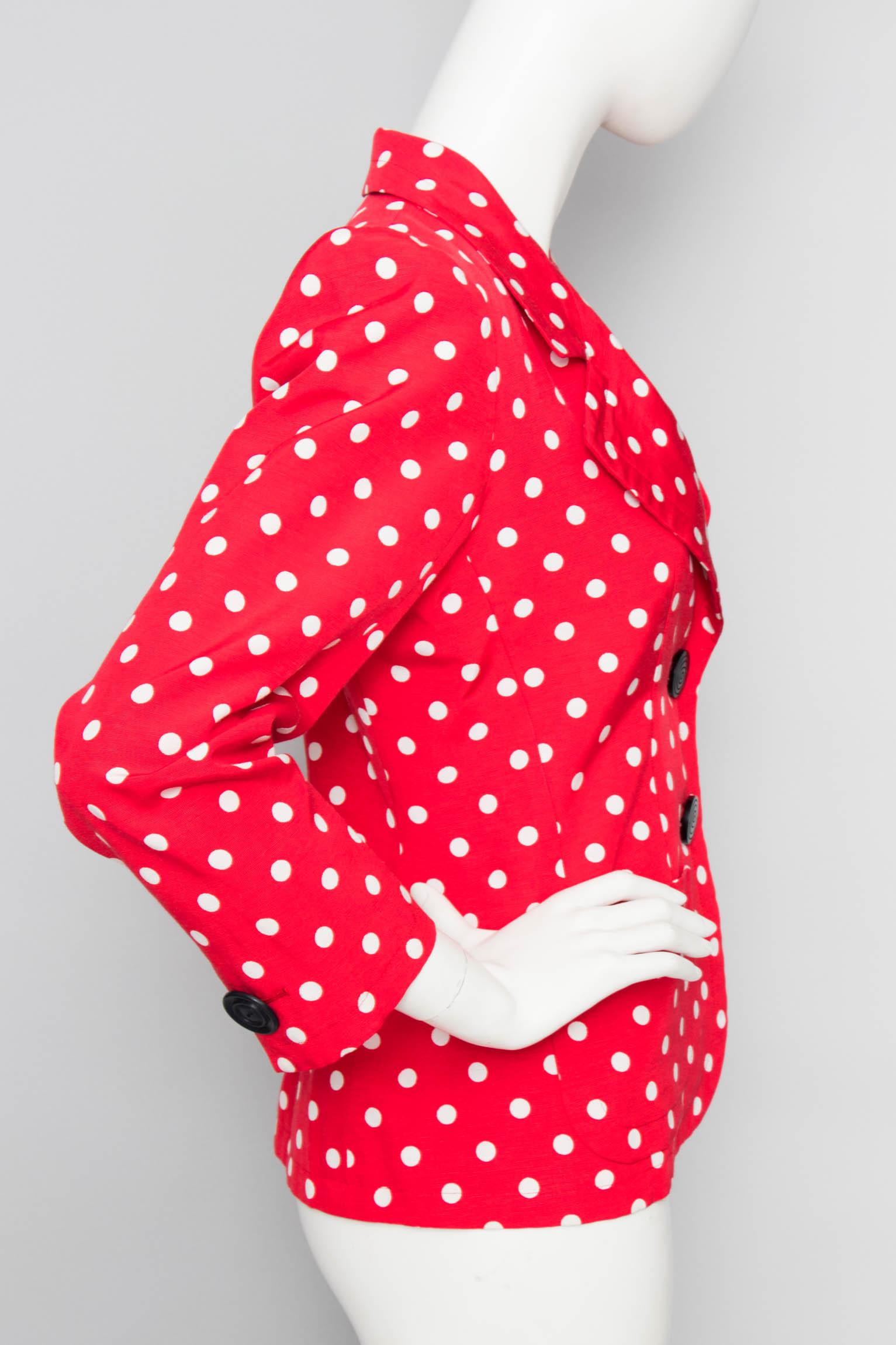 A 1980s Yves Saint Laurent bright red Rive Gauche blazer with white polka dots and large black buttons. The jacket has exaggerated shoulders, a narrow waist and long sleeves that all give the right 1980s glamour. The jacket is fully lined. 

The