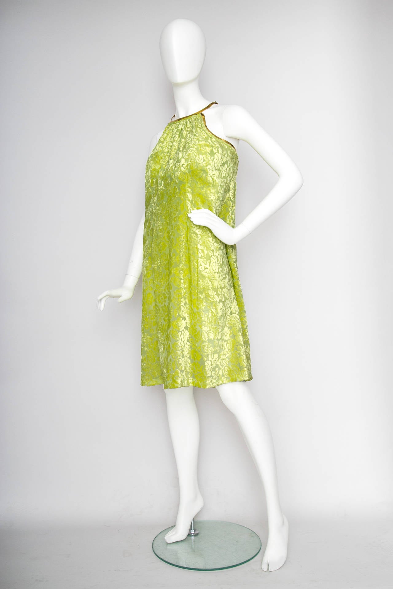 A stunning 1960s bright green a-line part dress with a burned velvet overlay. The dress has gold framing around the neckline and around the shoulders gathering the dress in the back. 

The dress closes in the back with a single hook & eye