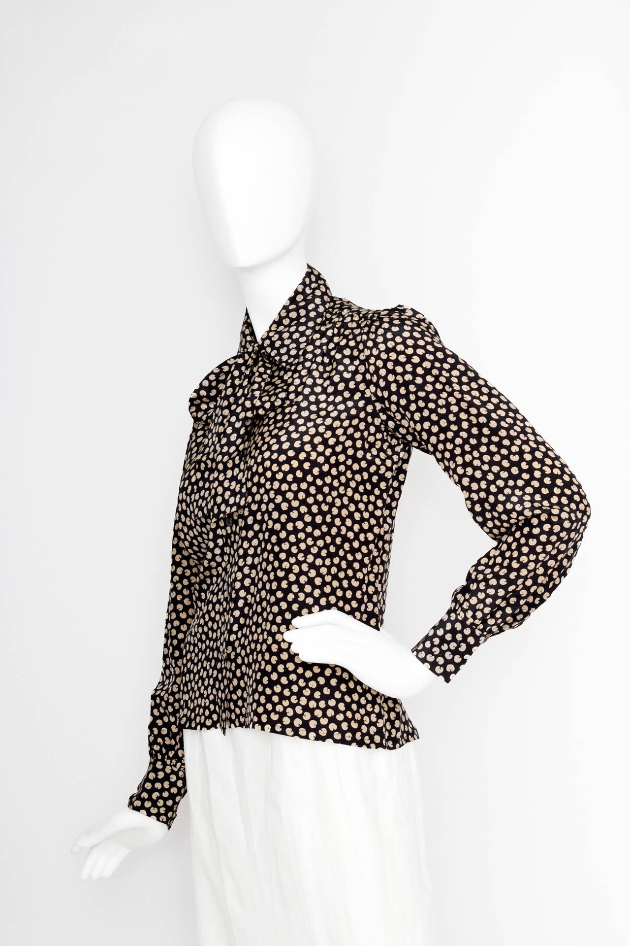 A 1970s black Yves Saint Laurent silk shirt with a pussy bow detail, one buttoned cuffs, a front button closure and an all over abstract print.

The shirt is equivalent to a modern size Small.