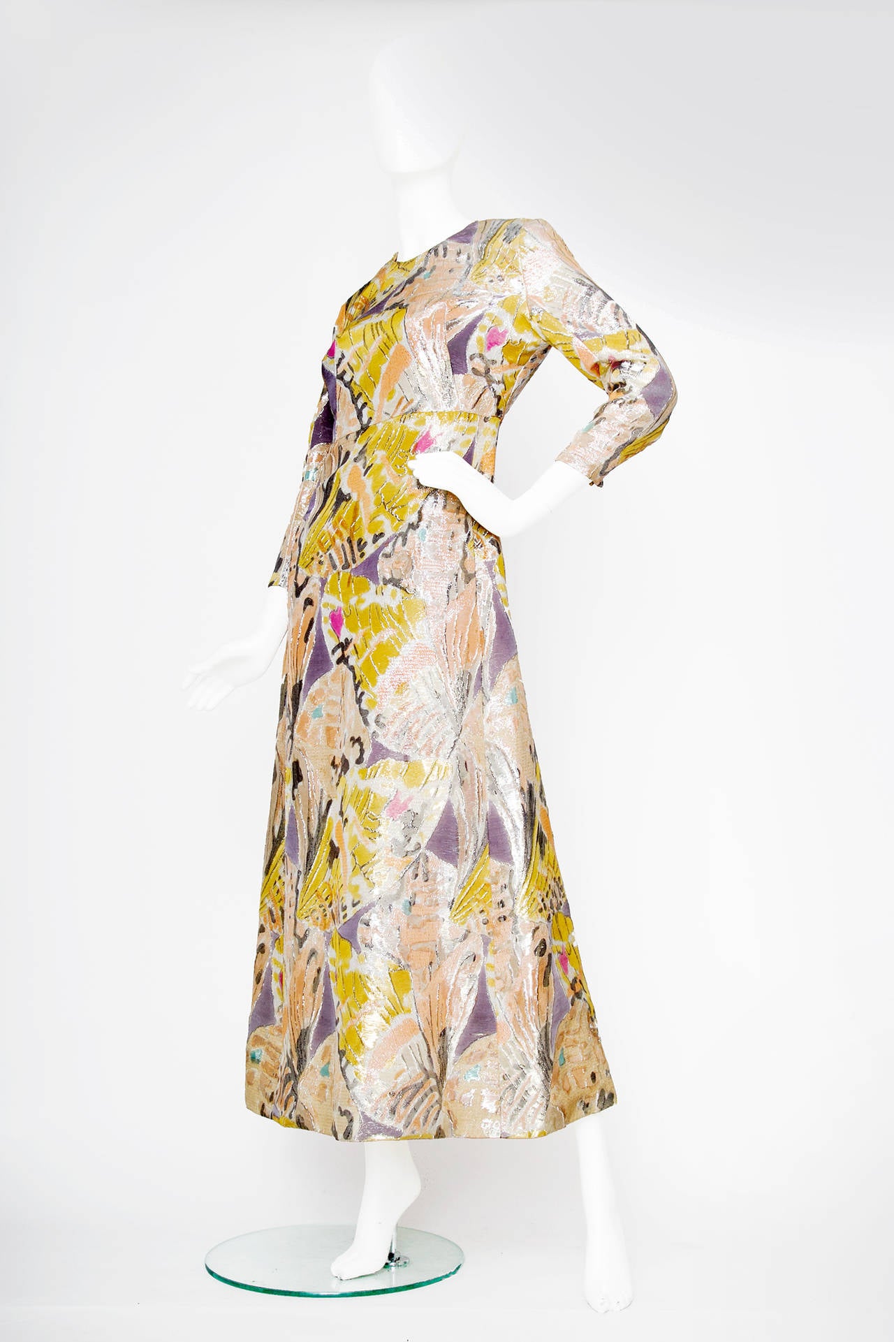 An absolutely stunning 1960s Givenchy gown with silver lurex thread and an all over abstract pattern in various pastel colours. The dress has long tapered sleeves with a metal zipper fastened at the cuff and a round neckline. The dress is narrow