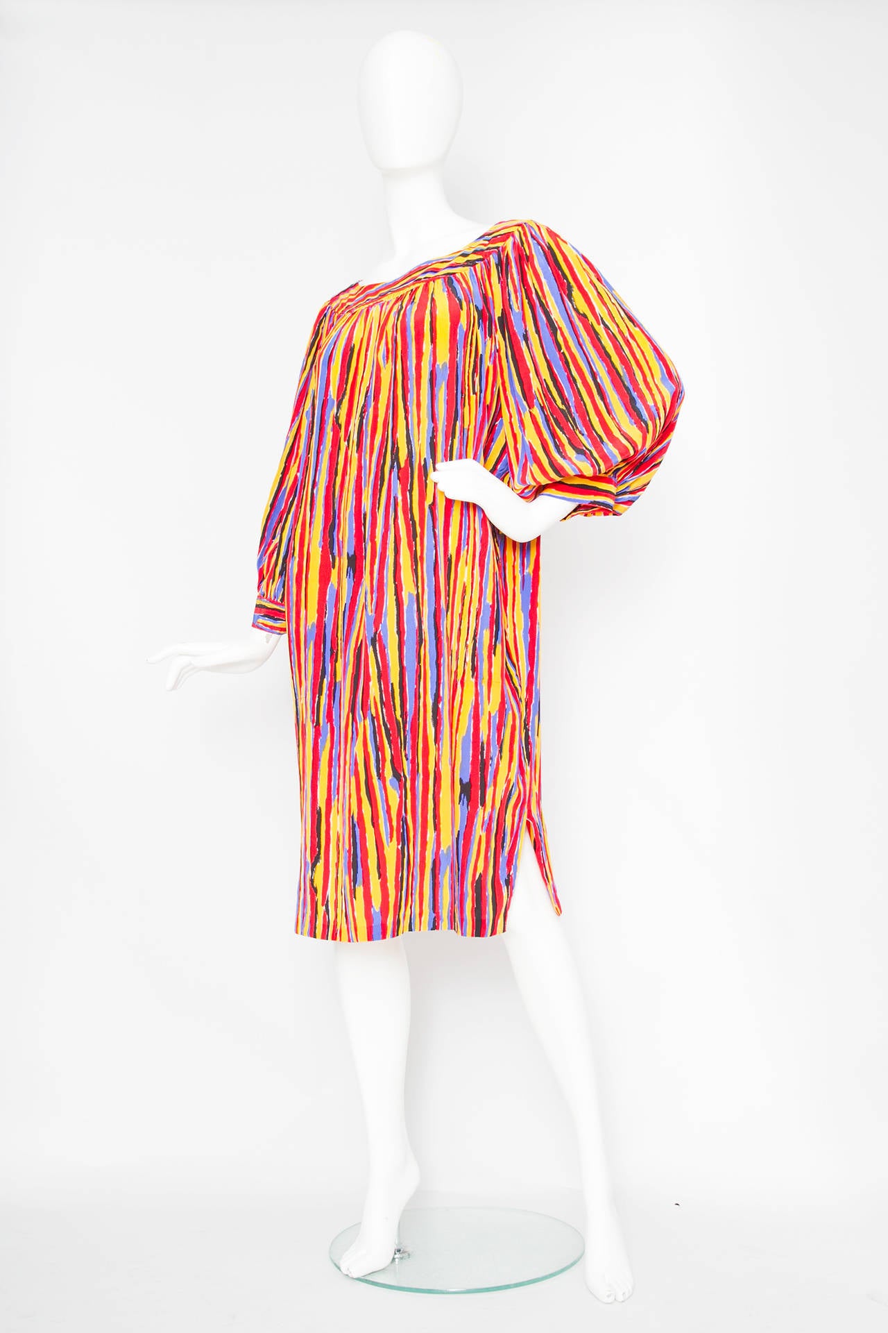 A stunning 1980s Yves Saint Laurent vibrant tent dress with an overall graphic print in bright red, yellow and blue. The dress has exaggerated three quarter length balloon sleeves, a scoop neckline and a slit on the lower side of the hem. The dress