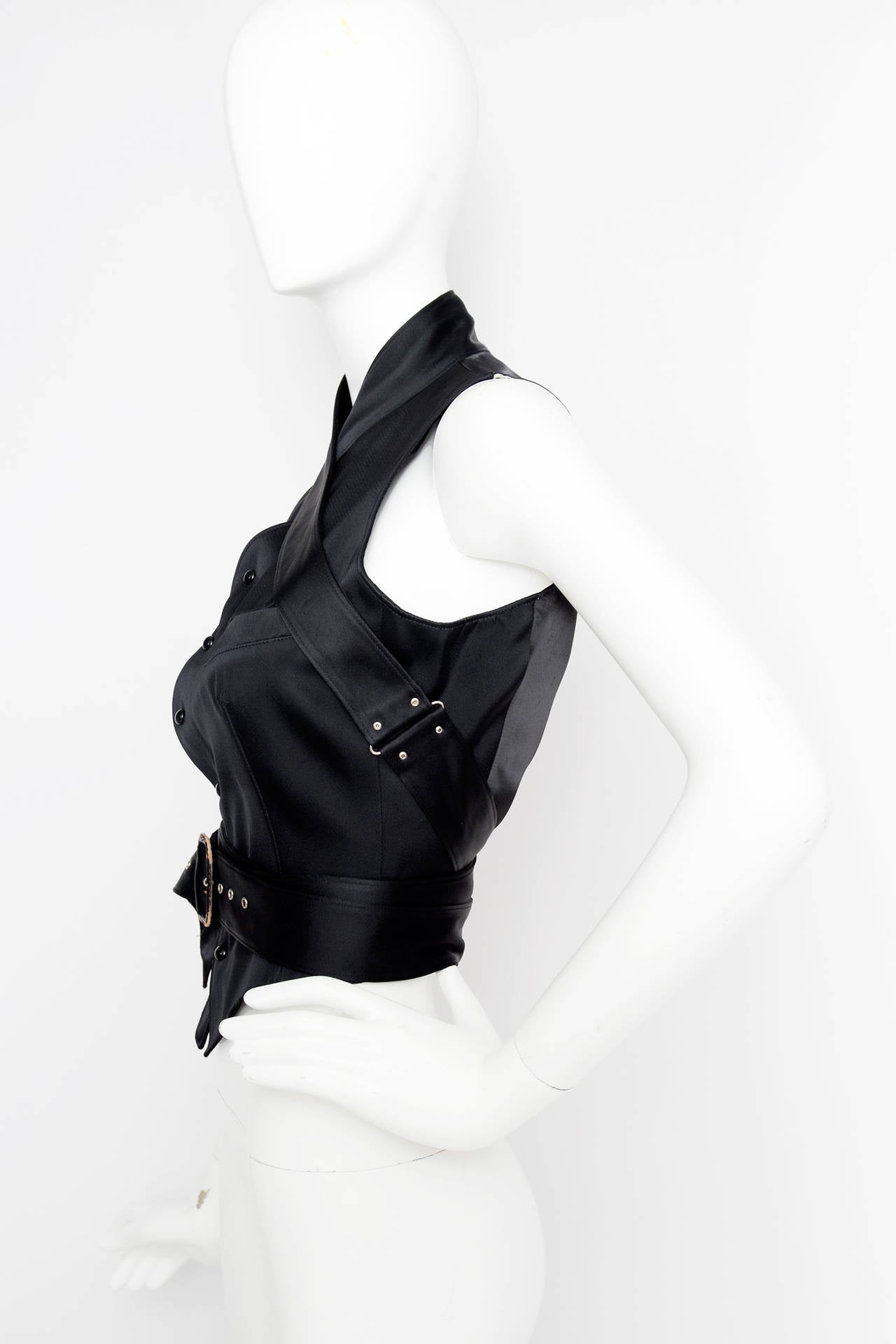 A 1990s Jean Paul Gaultier  waistcoat with two welt pockets on the bust and a front button closure. The waist coat has a double waist belt that is attacked to the neckline and ties in the front with a buckle closure. The waistcoat has a contrasting