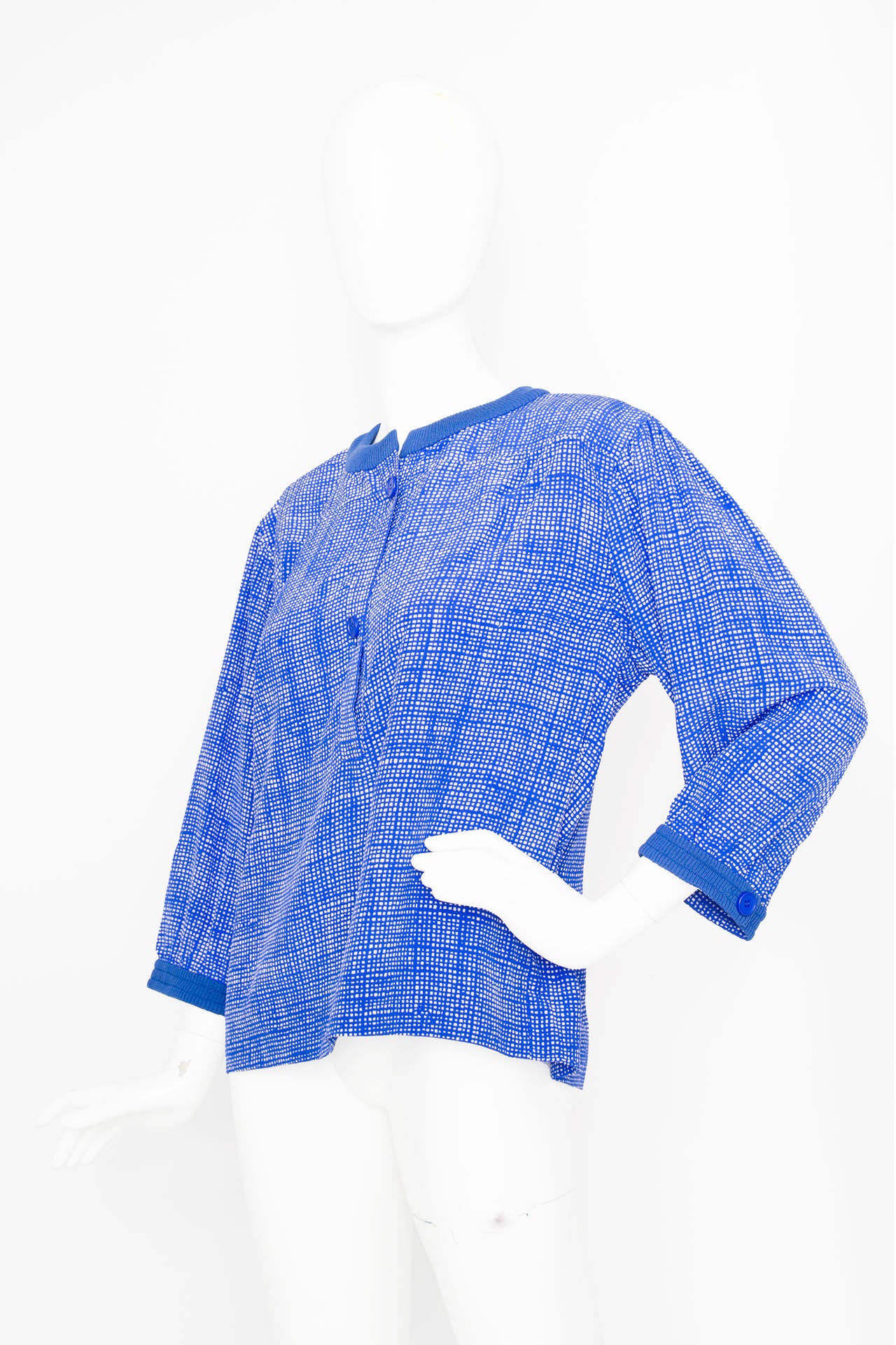 A 1980s Givency Haute Couture silk blouse with an allover blue and white graphic print. The blouse has one buttoned cuffs and a button down front. Around the neckline and cuffs the blouse has a solid blue ripped trimming. The blouse has three