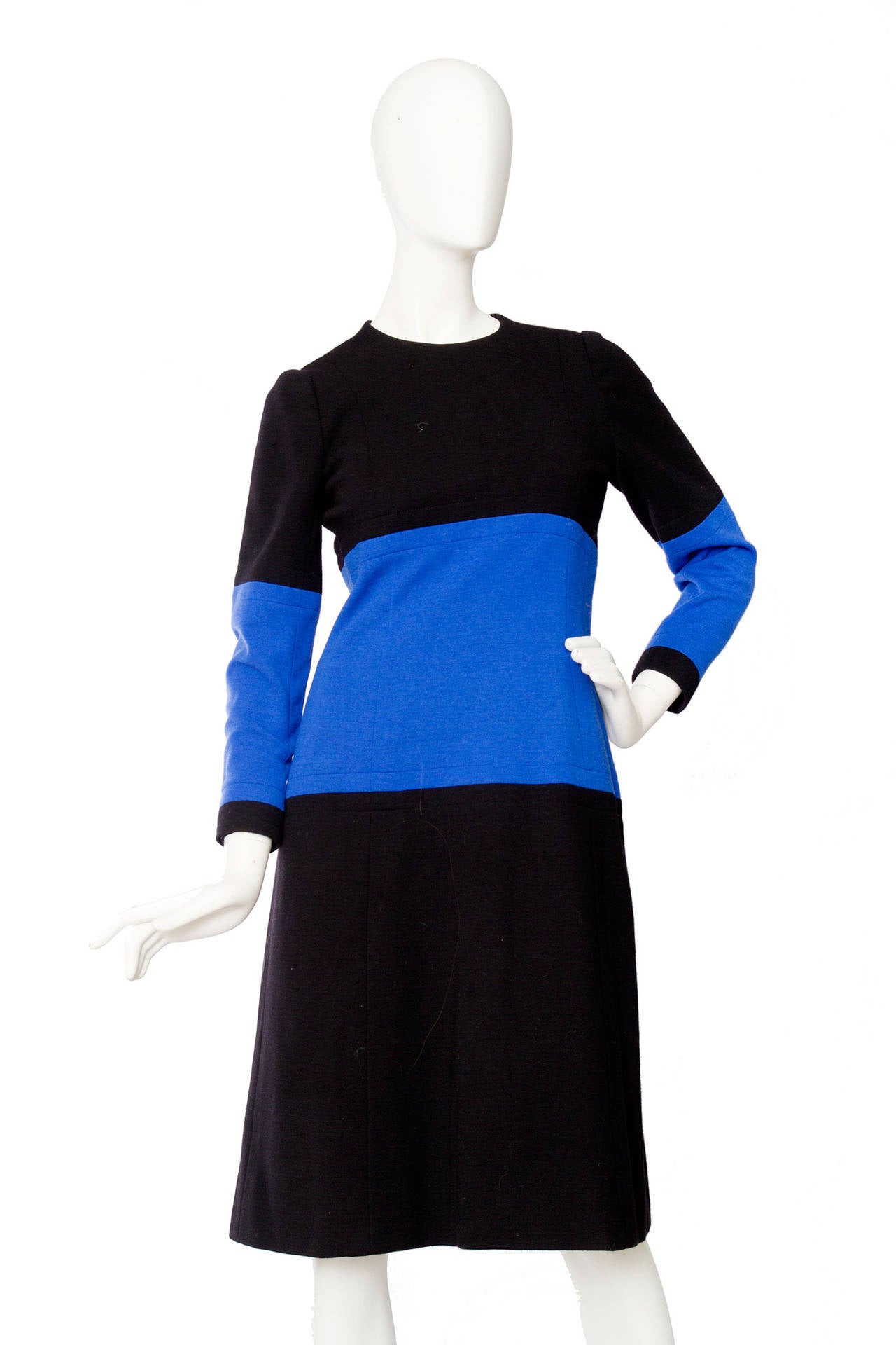 A 1960s Givenchy haute couture black wool dress with a bright blue panel detail across the midriff and sleeves. The dress is fully lined, has a round neckline and closes in the back with a metal zipper closure. 

The dress is numbered: