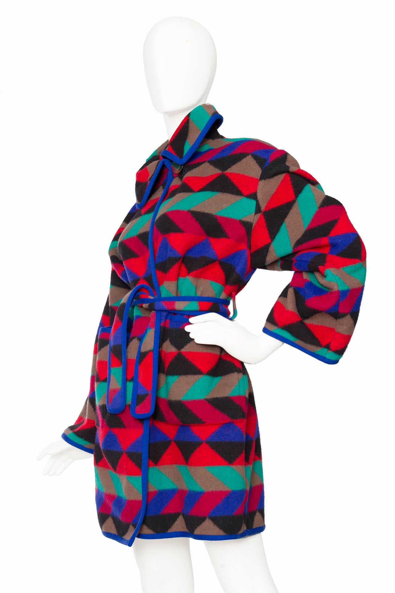 A 1980s Missoni wrap coat in bright colours. The coat has a single top button closure, a matching belt to tie around the waist and two patch pockets to the front. A matching blue trim gently frames the coat.

The size of the coat corresponds to