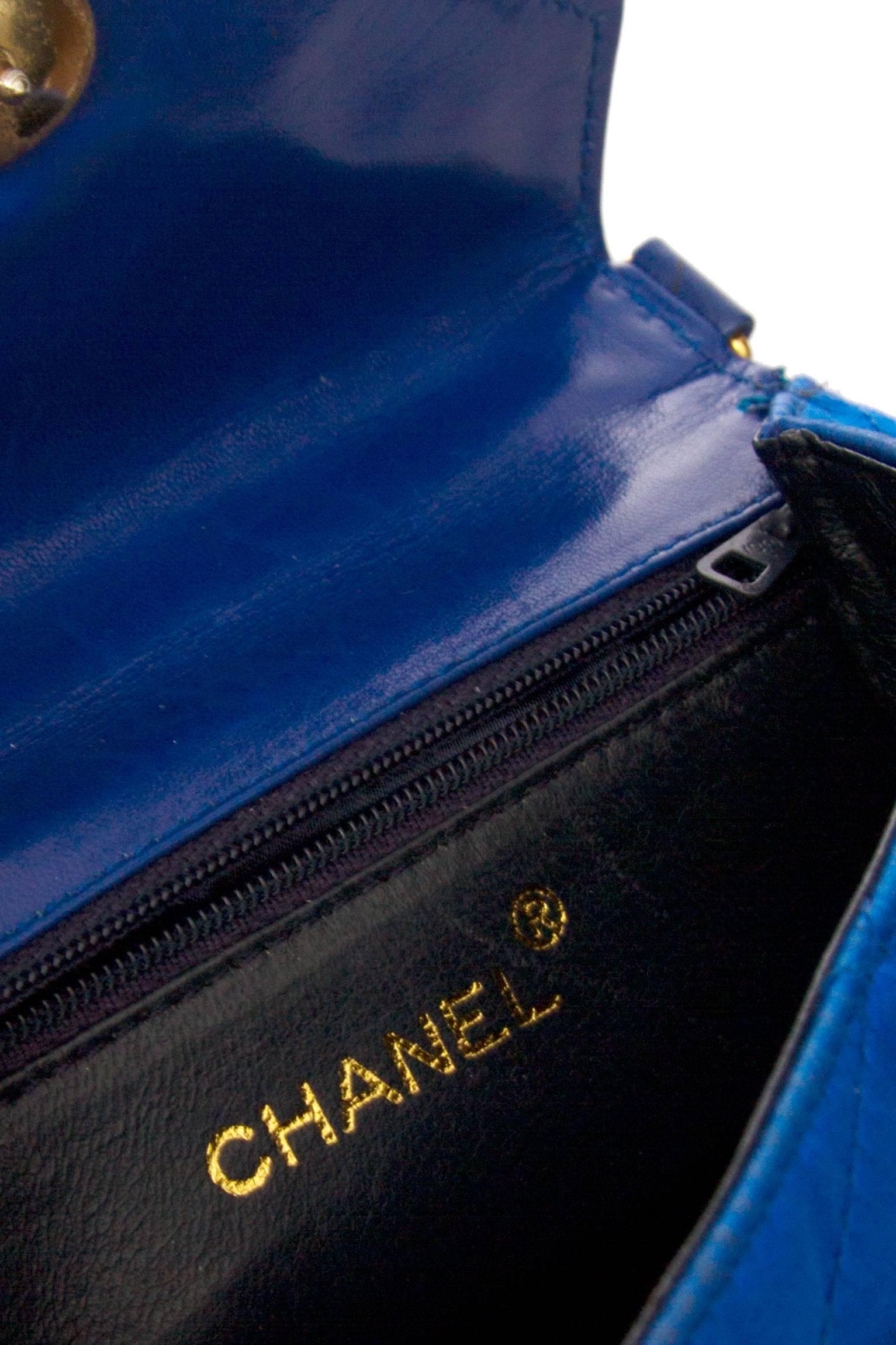 A late 1980s original Chanel electric blue quilted satin evening bag with gold hardware. The bag has a v-shaped closure which is fastened by one large gold button with rhinestone settings. The glamorous gold chain is made up off five individual