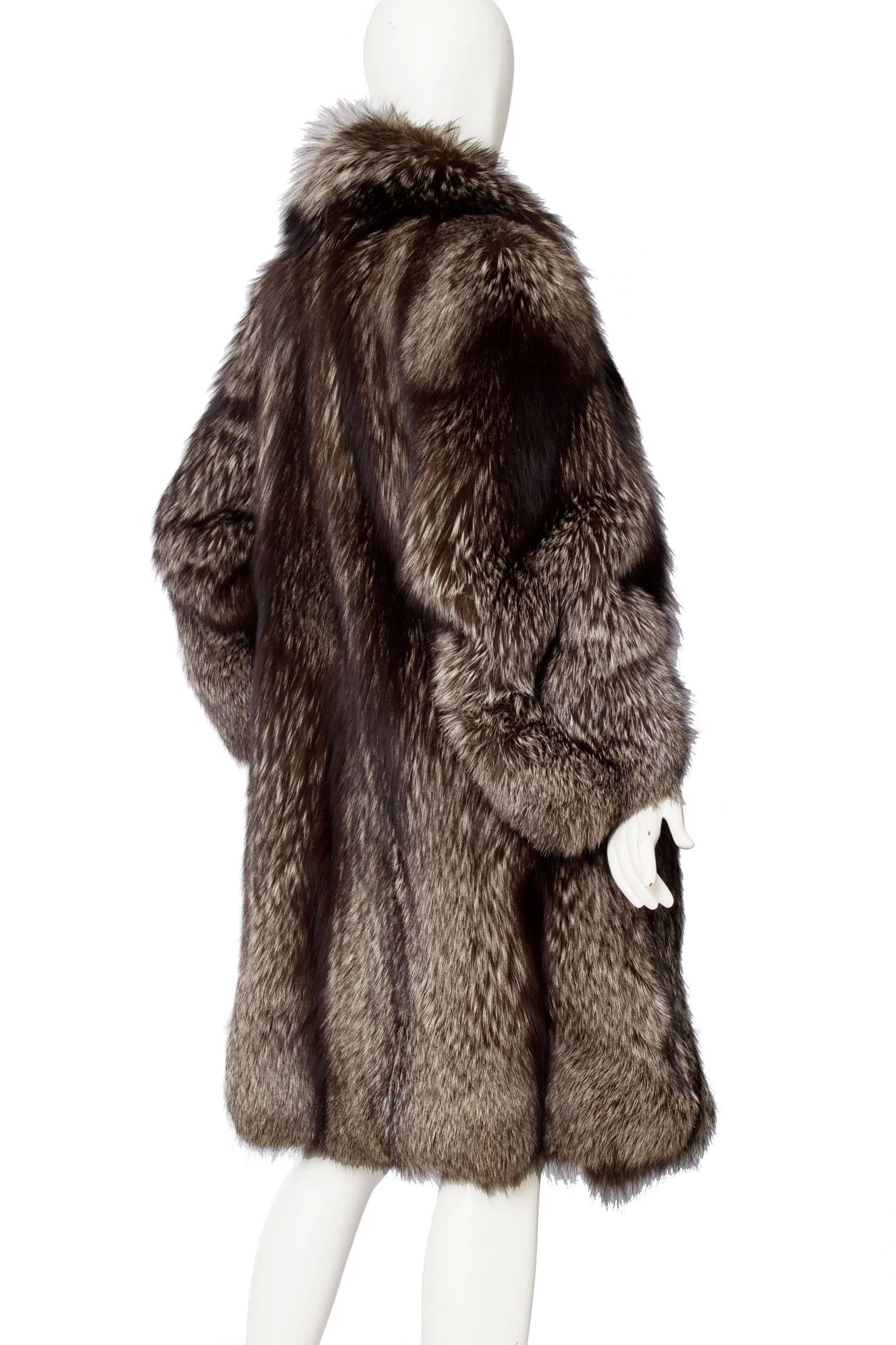 A glamorous 1980s silver fox fur coat with extravagant shoulders and voluminous sleeves. The coat has side pockets and beautiful detailed paneling running down the back.  

The size of the coat corresponds to a modern size Medium. 