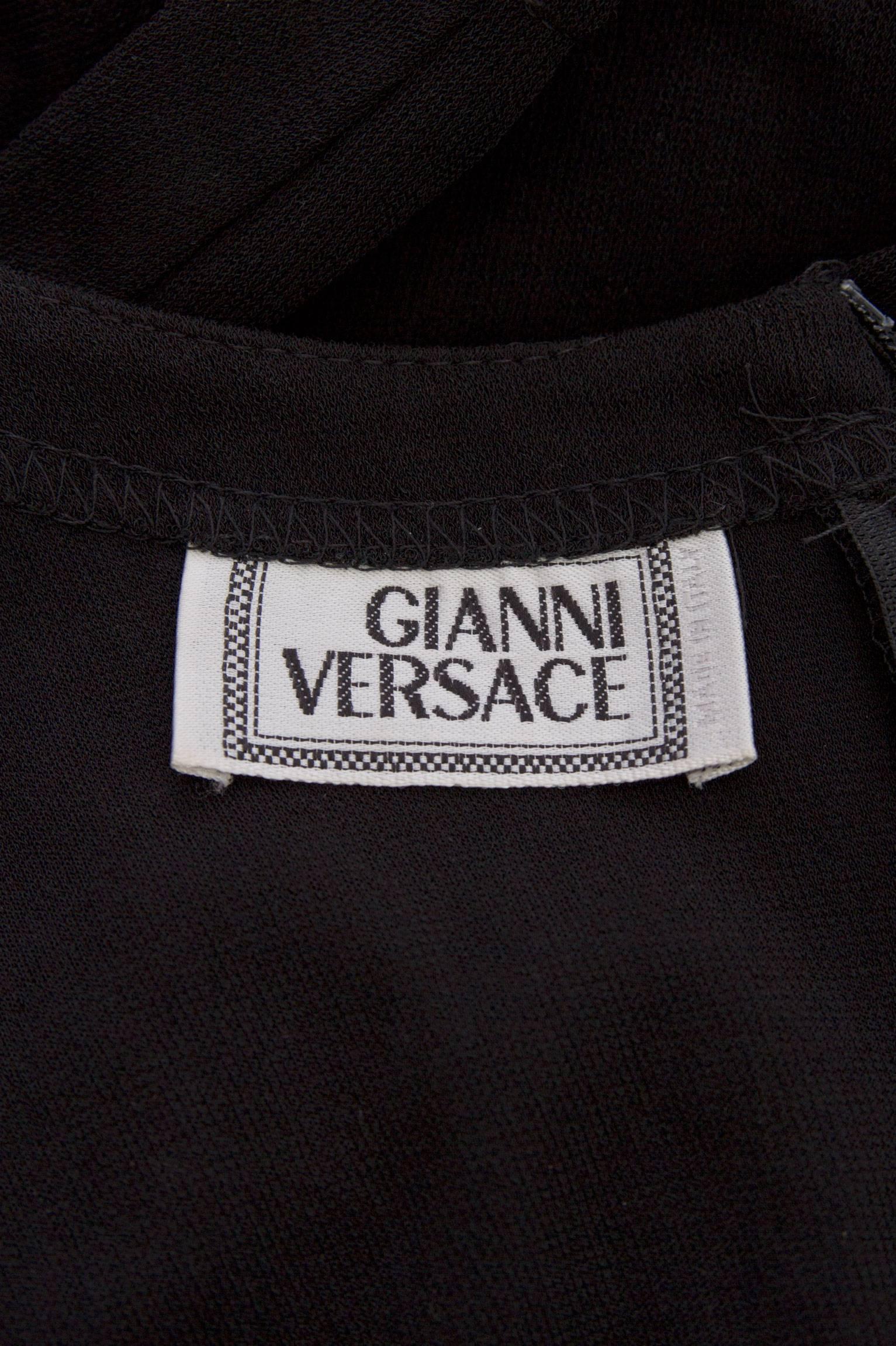 A simple 1980s little black Gianni Versace silk jersey dress with a fitted bodice, long tapered sleeves and a pleated drop mini skirt. The dress has a round neckline and a back zipper and hook & eye closure. 

The size of the dress corresponds