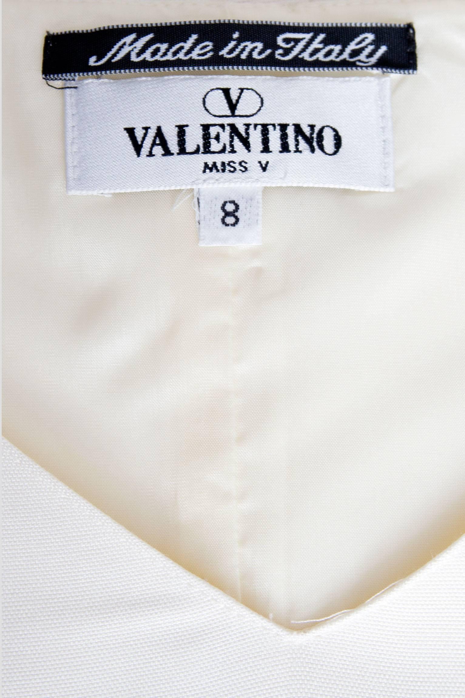 A lovely 1980s Valentino Miss V off-white silk dress with cap sleeves and a demure v neck in the front. A simple skirt cuts just below the knee and a drop waist with a beaded belt detail gives the dress an ekstra feminine touch. The cylinder shaped