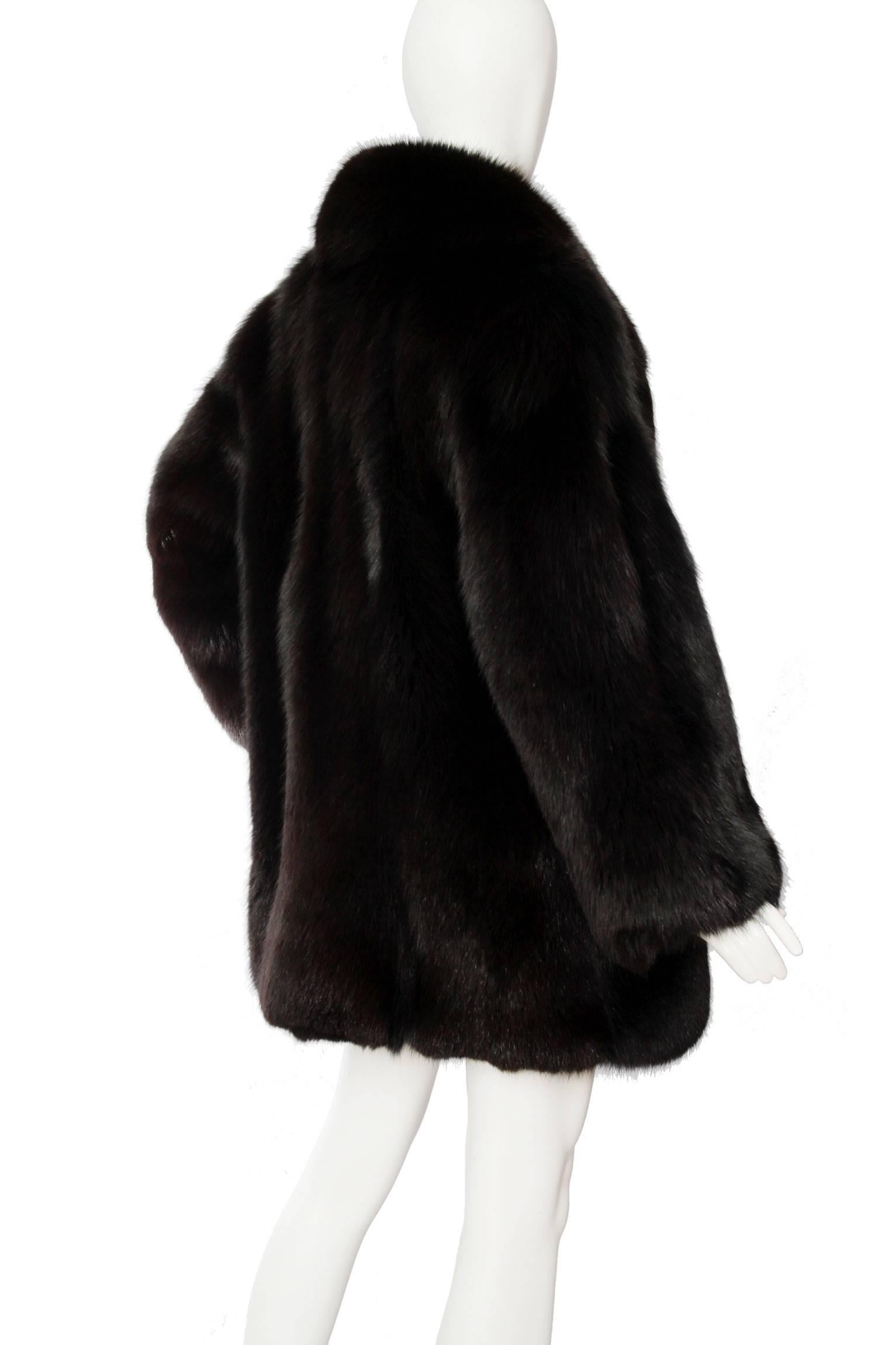 A glamorous 1980s black blue fox fur coat, exaggerated sleeves and a voluminous collar. The coat has side pockets and a matching black lining. 

The size of the coat corresponds to a modern size Medium. 
