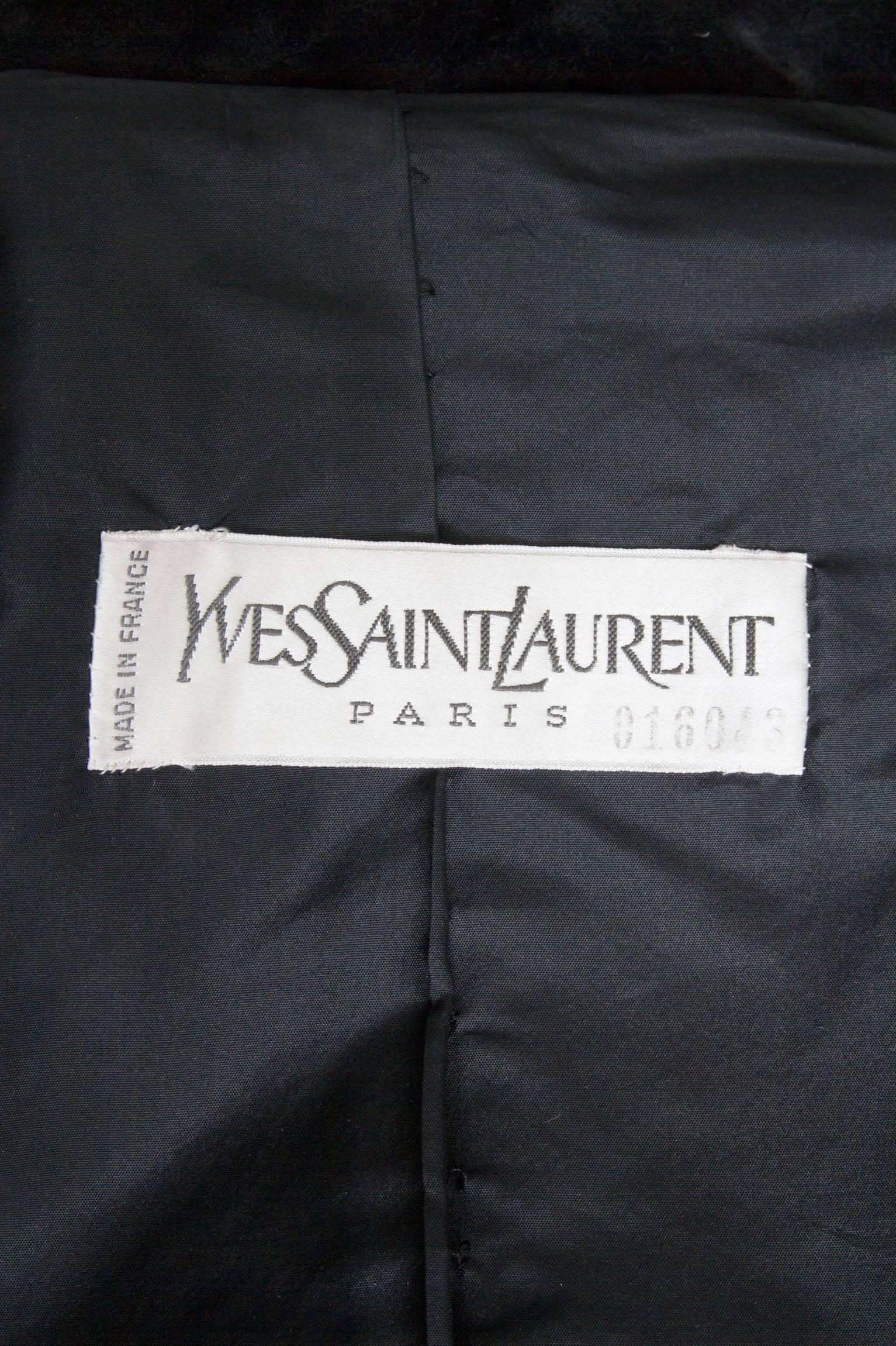 A 1970s Yves Saint Laurent black fitted suede haute couture jacket with long tapered sleeves and a full front button closure. In the front the jacket has two patch pockets on each side of the lower body. The pockets close with a single button and