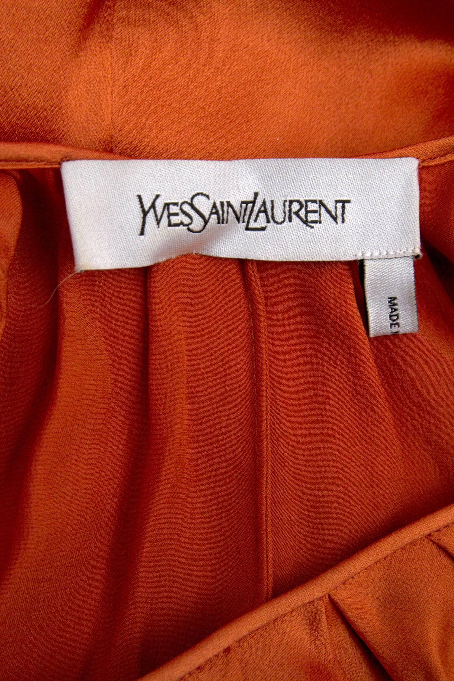 A gorgeous 1990s beuatifully draped Yves Saint Laurent silk dress made in a soft tangerine colored silk. Loose draped sleeves are attached to the round neckline and decent below the arms and is attached to the back, providing volume to the side of