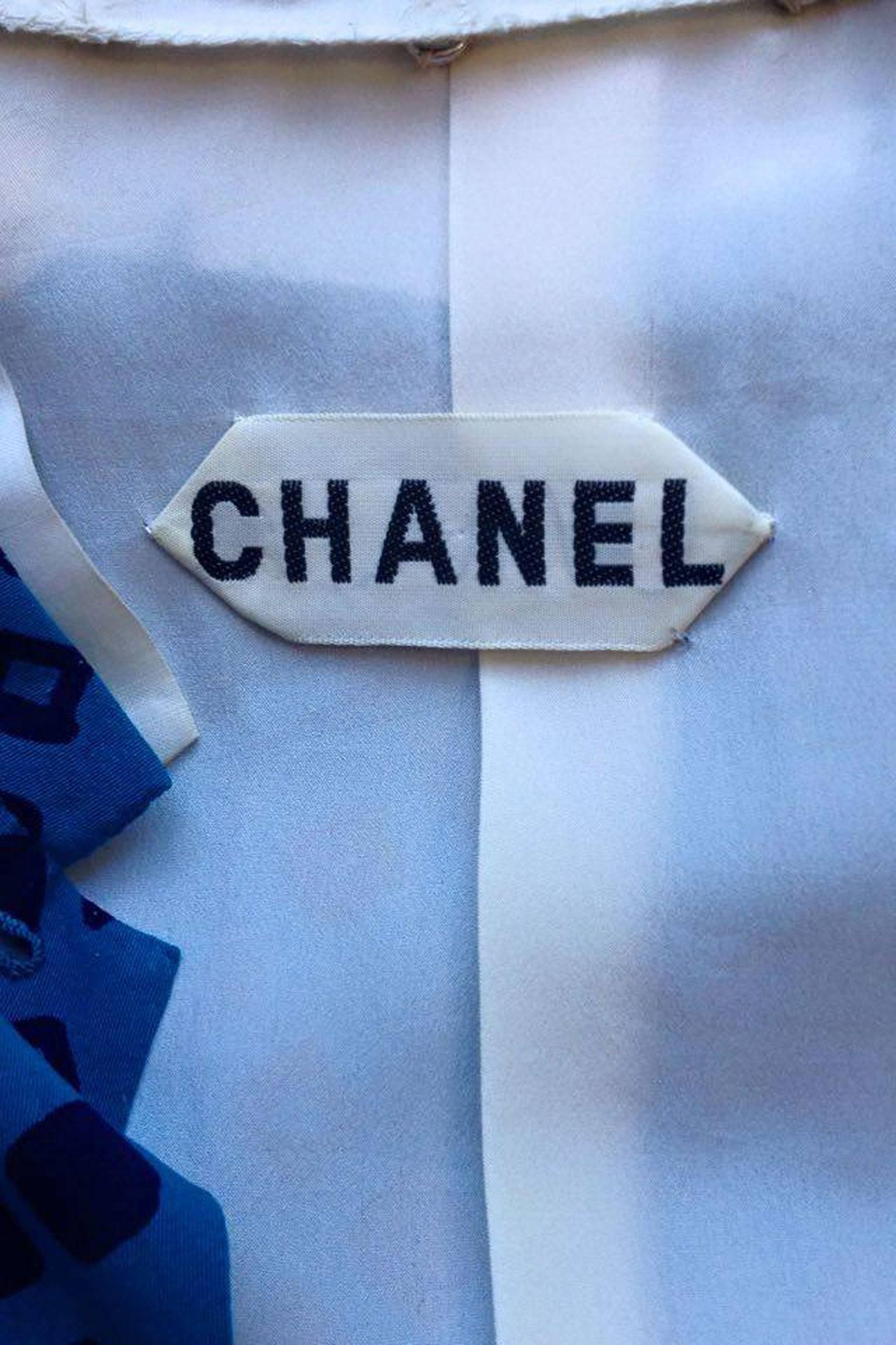 A stunning 1960s bright blue Chanel silk skirt suit with black graphic print consisting of a pleated skirt and fitted jacket. The jacket has a rounded neckline with a white ruffled and detachable cotton collar and white detachable cuffs. In the
