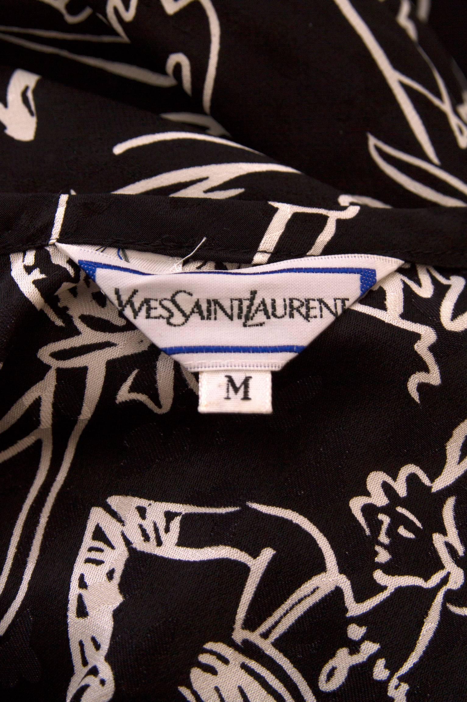 A gorgeous black 1980s Yves Saint Laurent summer day dress with a full skirt and short sleeves. The loosely fitted dress can be held together at the waist by a detachable matching waist belt, which can be tied around the waistline. The jacquard
