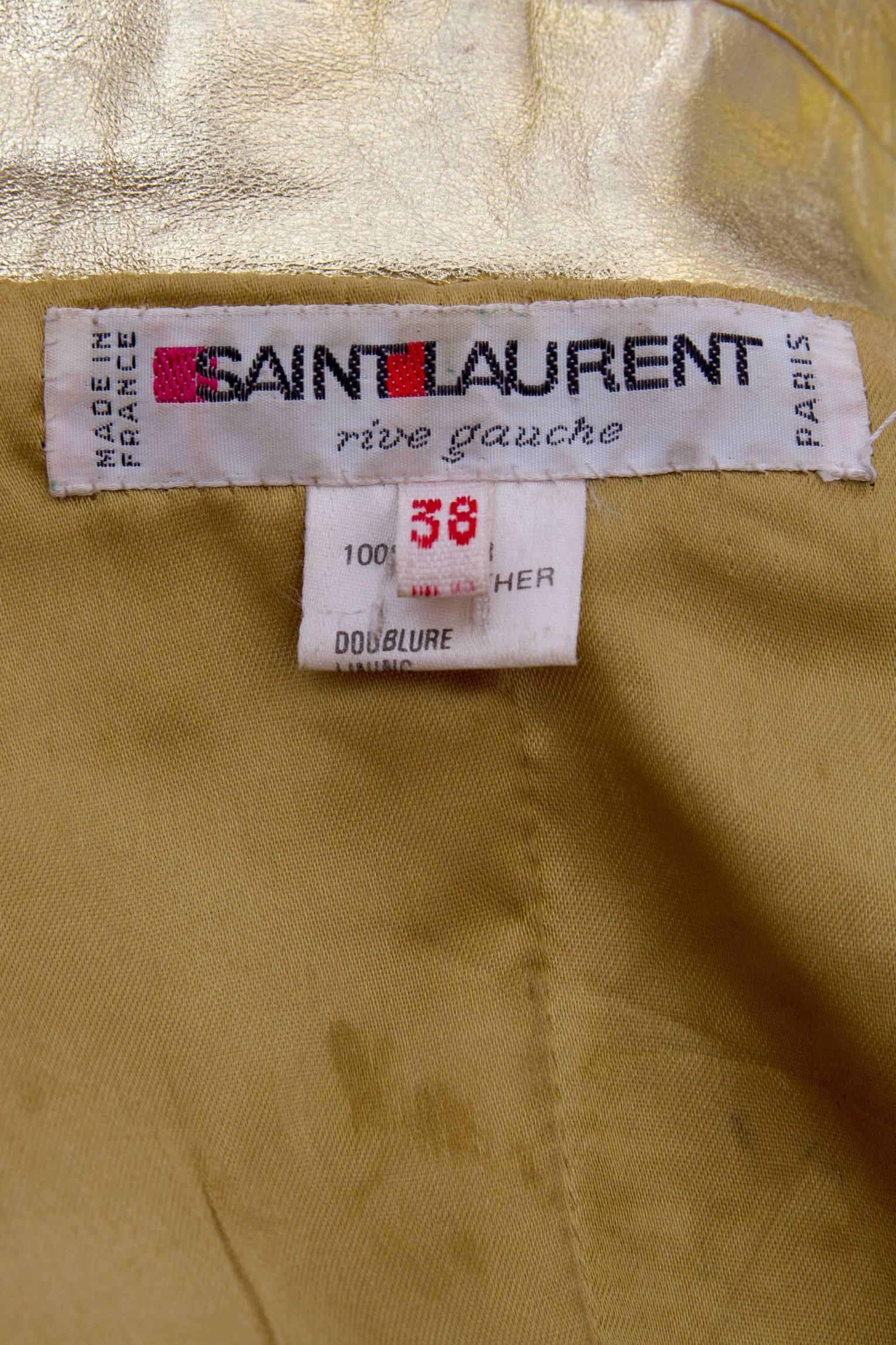 A 1990s high voltage glamour Yves Saint Laurent double breasted gold leather jacket with exaggerated shoulders and wide lapels. Four large rounded gold buttons ads definition to the waistline and two large patch pockets on each side of the hip gives