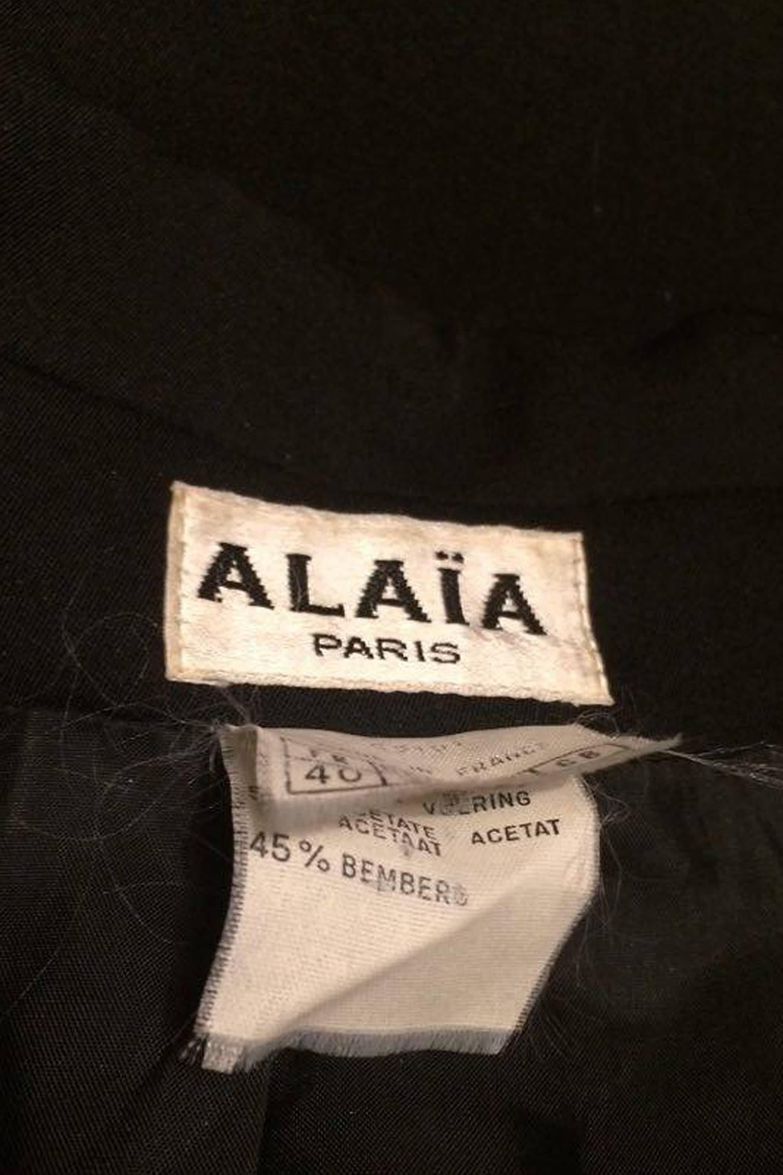 A classic 1990s black cropped Alaïa blazer with a deep v-neckline, slim lapels and a double buttoned closure. Structured shoulders are held in place with small shoulder-pads and one buttoned cuffs ads deal to the excess length sleeves. The blazer