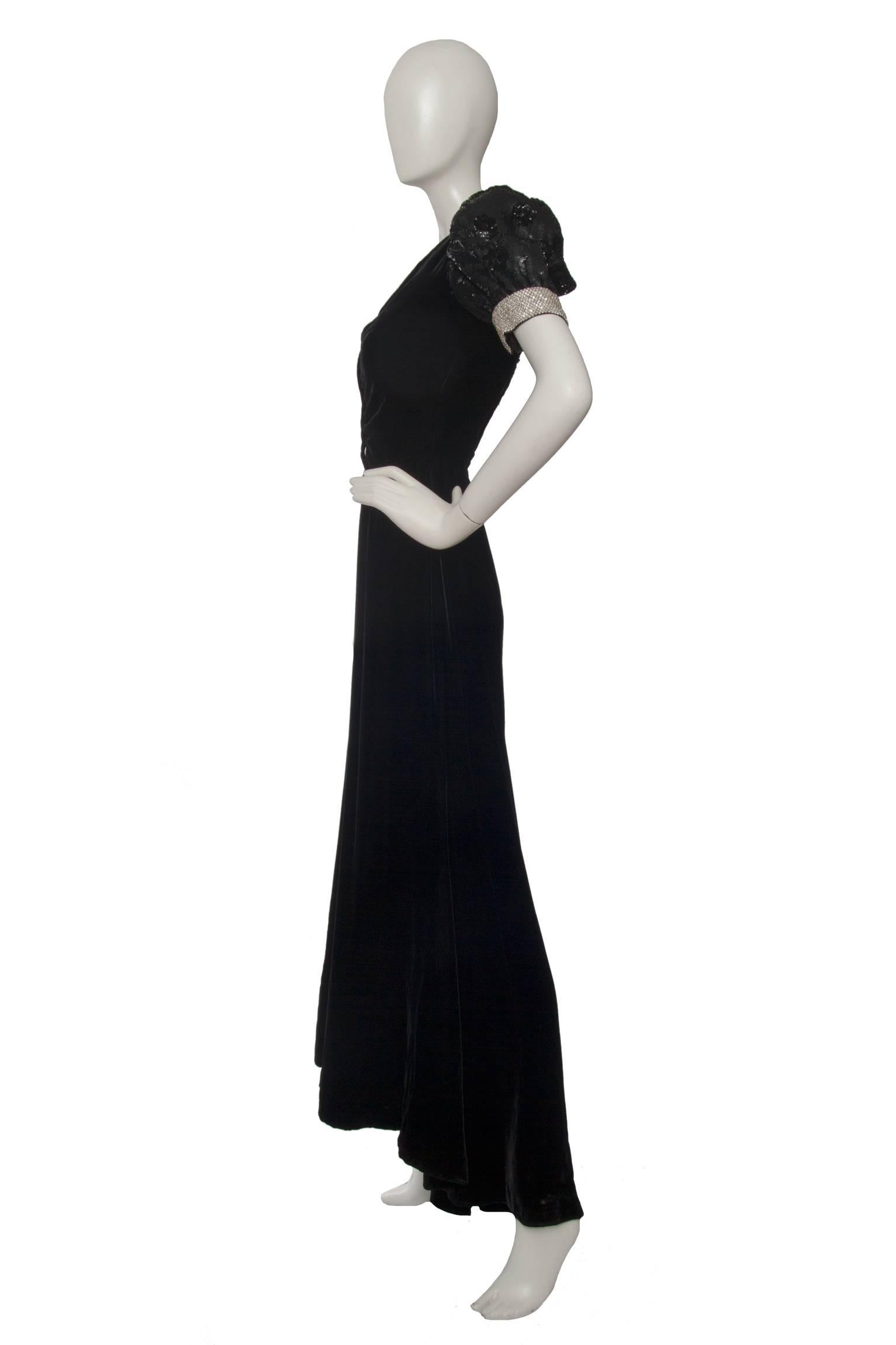 A gorgeous 1980s Valentino Nigh black velvet gown with a fitted bodice, embellished puff sleeves and an hemline which is slightly longer at the back. The black sequin decorated sleeves is set in a polka dot pattern and a contrasting trim of white