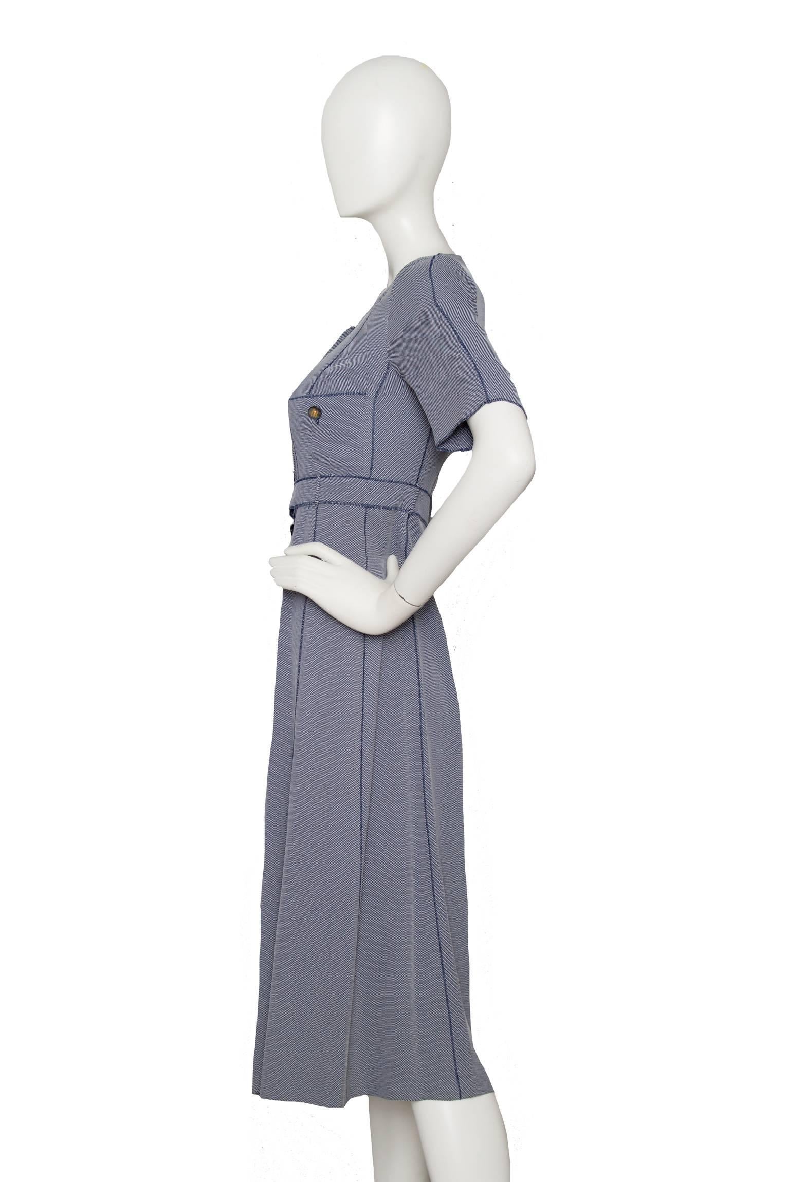 A 1990s blue Chanel midi length day dress with short sleeves, a round neckline and full button-down front. A build-in waist belt with a buttoned closure brings definition to the waist and two breast pockets with a button closure adds detail to the