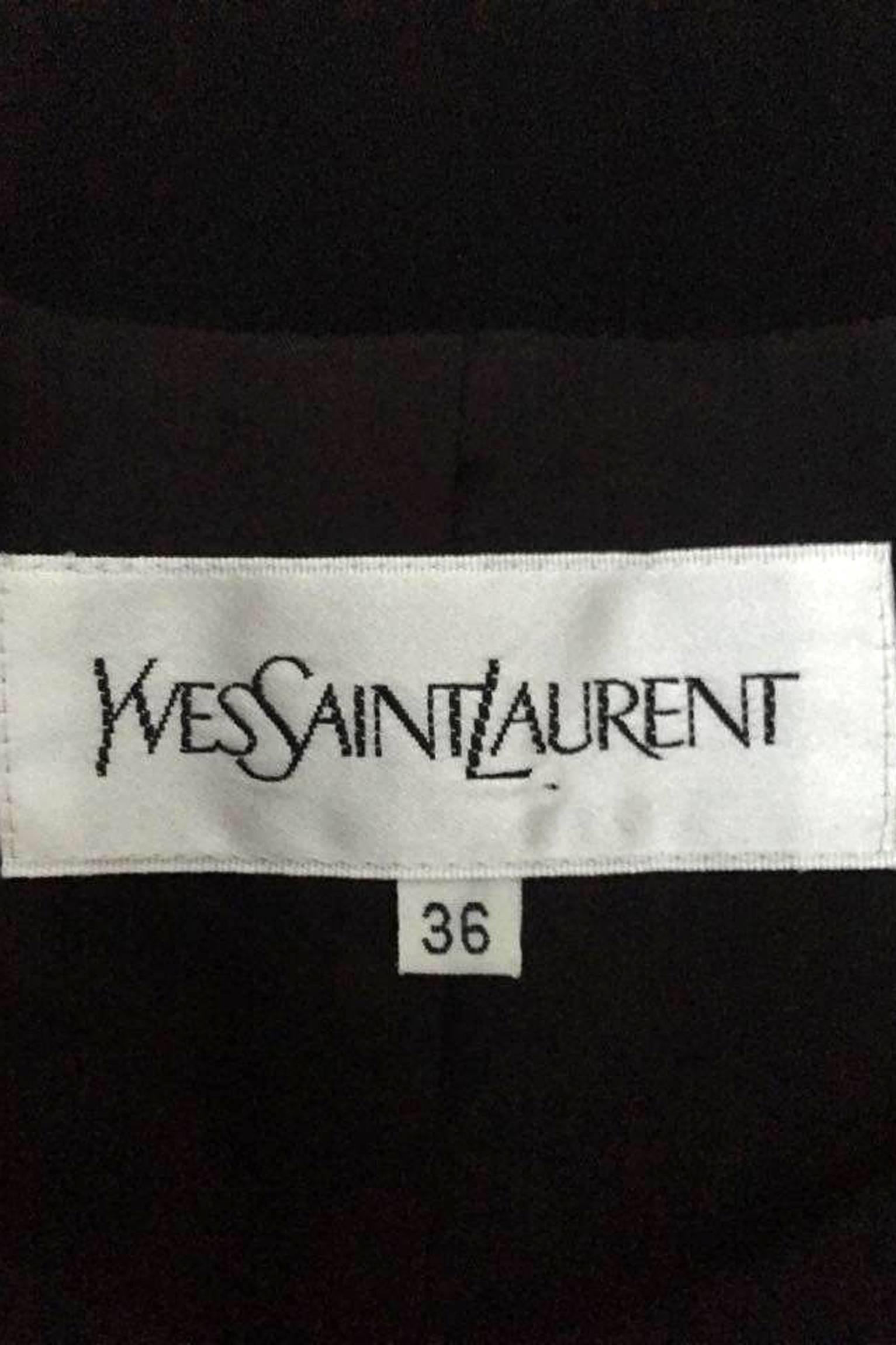 A 90s Yves Saint Laurent black wool dress with structured shoulders, a flared skirt and tapered sleeves. The dress is fully lined and has a pocket situated on each side of the lowered waistline and a single mock pocket on the left side of the bust.