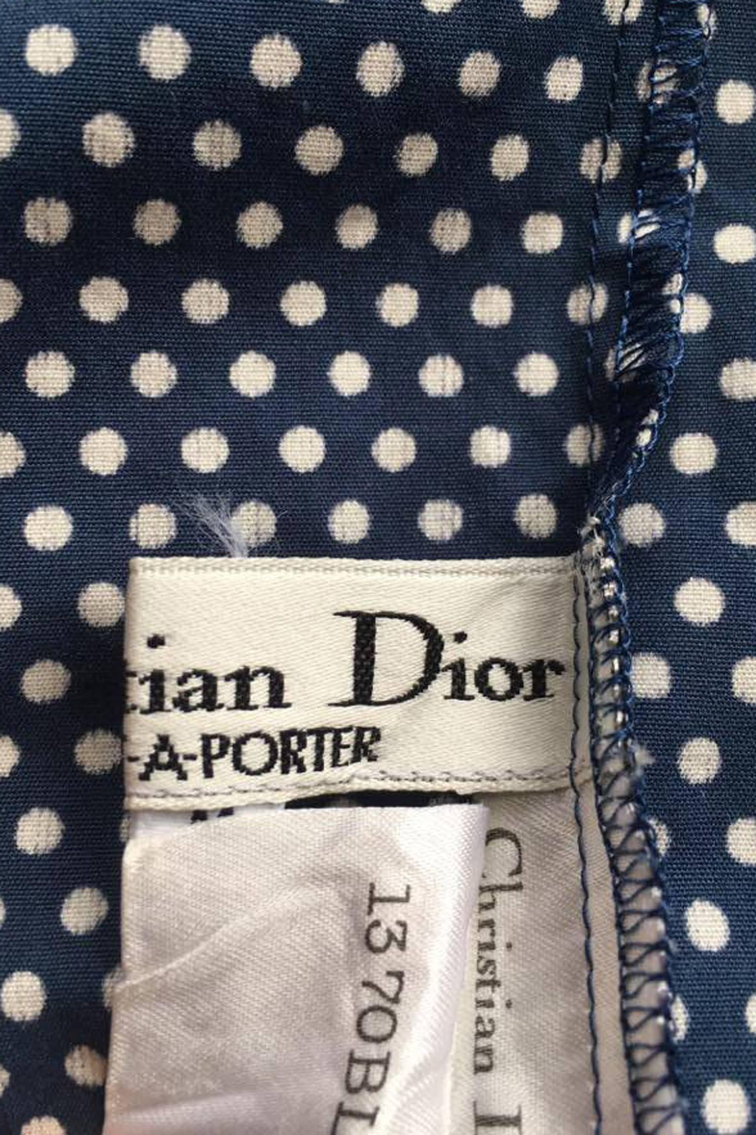 A gorgeous 1980s blue Christian Dior cotton blouse with white polka dots and a large ruffle collar with white trimmings. The blouse has a hidden front button closure with just one visible top button which gathers the double ruffled collar in the