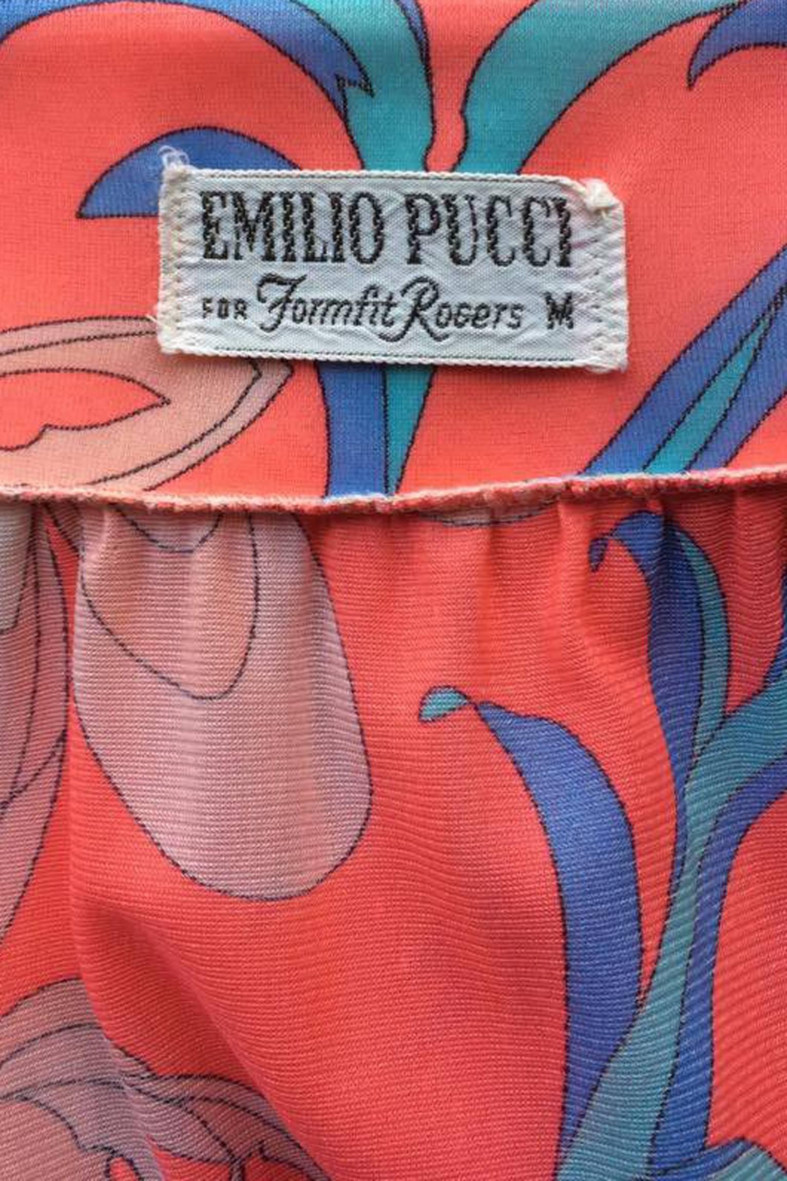 A pink 1970s Emilio Pucci nylon maxi dress with three-quarter length sleeves, a square neckline and an ankle-length a-line skirt. The dress has a large and bright floral prik which is held in a pale pink, blue and brown color scheme.  Along the