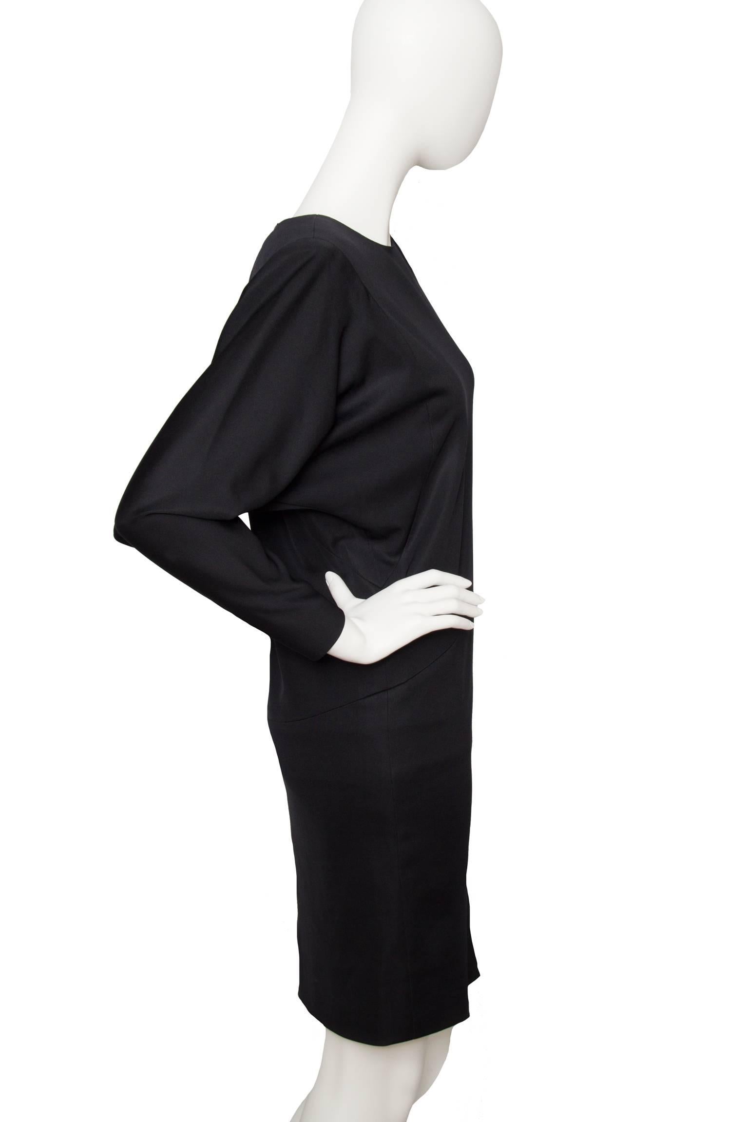 A 1980s black Yves Saint Laurent haute couture cocktail dress with a drop waist fitted skirt and a voluminous top with long sleeves tapered at the cuff. The dress has a round neckline, zipper details at the cuff and a zipper closure situated at the