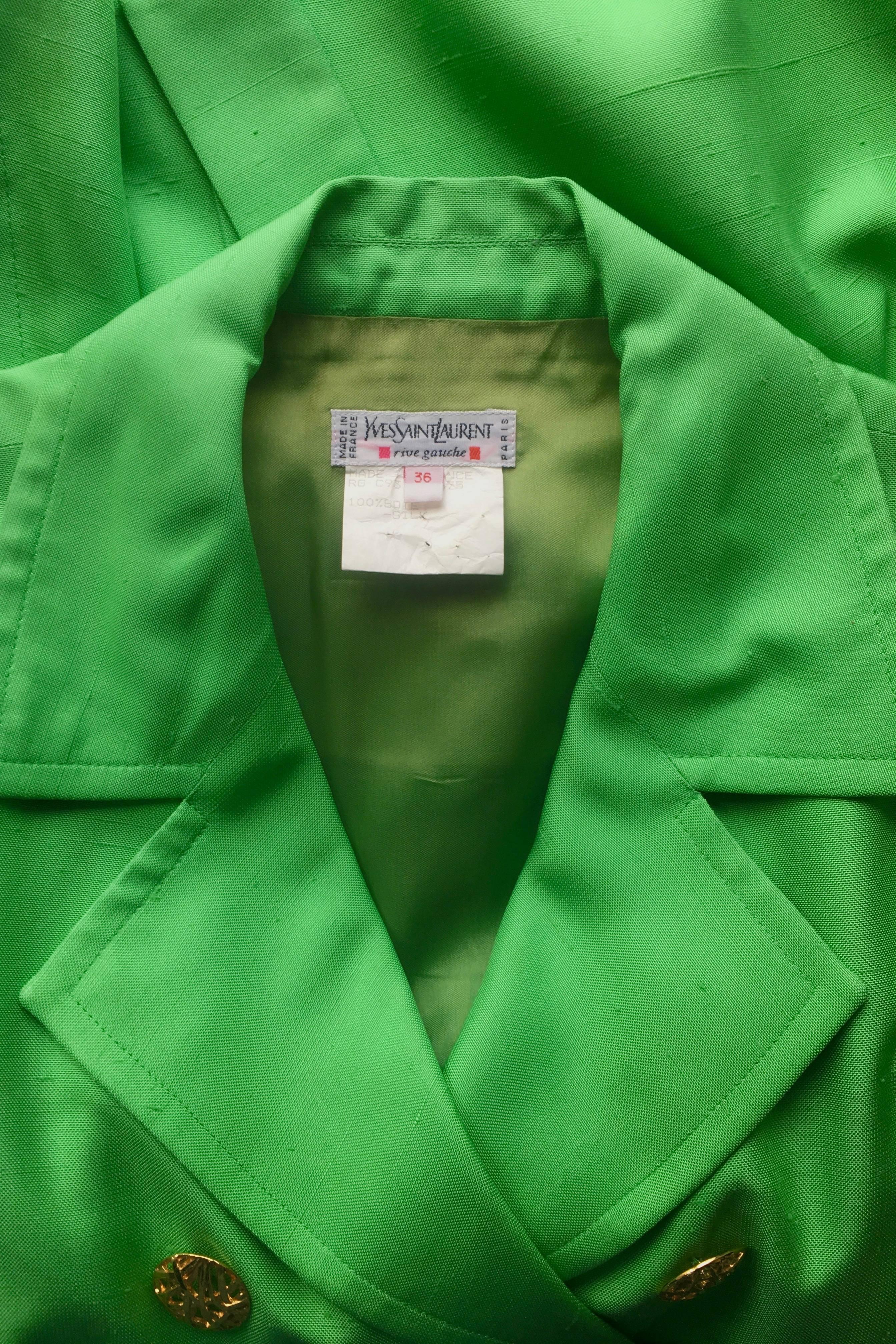 An incredible 1960s Yves Saint Laurent Rive Gauche bright green silk trench coat with a nipped in waist and double-breasted closure. The stunning coat comes with a matching waist belt with a gold buckle closure, which beautifully matches the