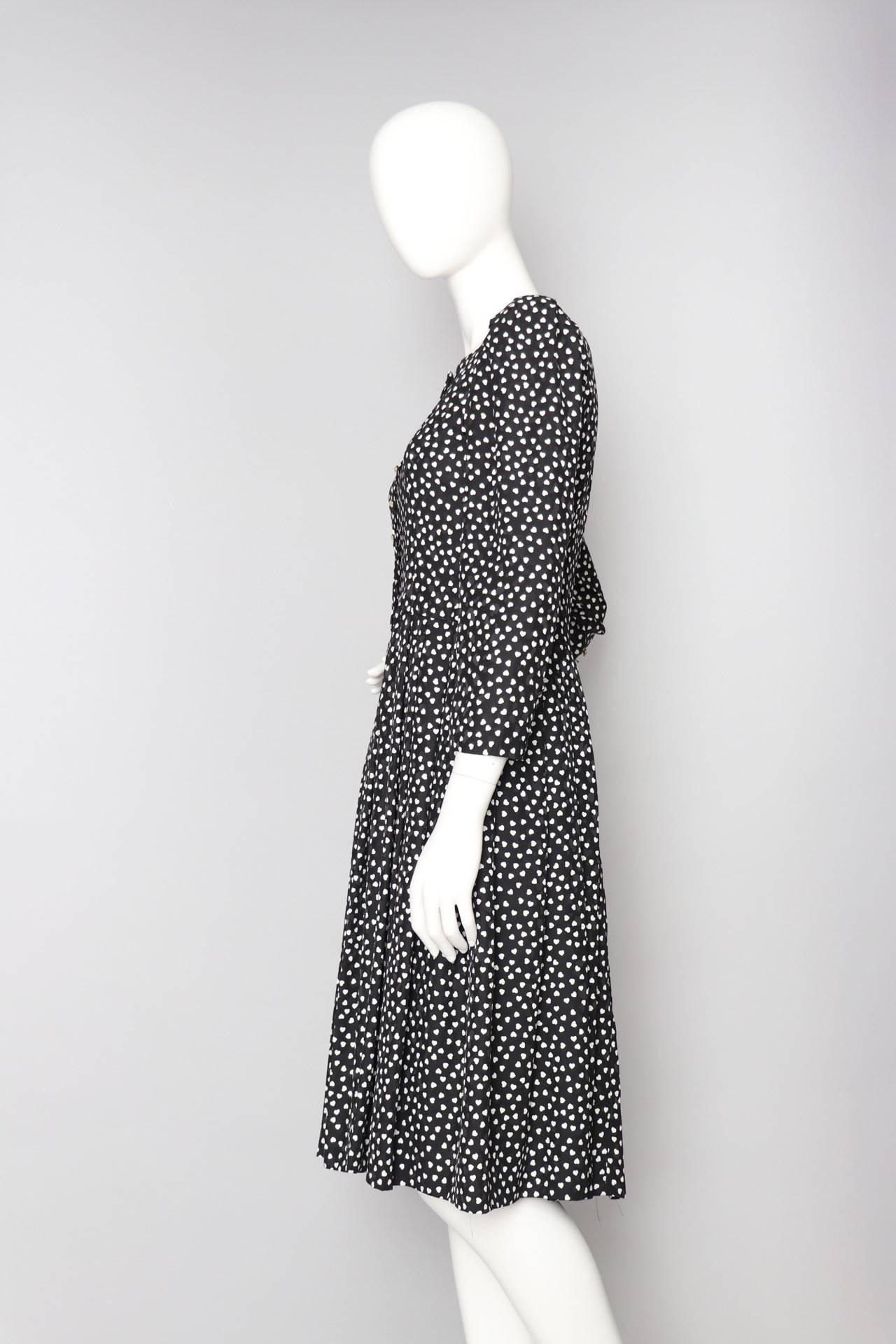 A great 1980s Hanae Mori black dress with a round skirt, long sleeves with pearl embellished cuffs, and a fitted waist. The dress has a round neckline and a back zipper and hook & eye closure. Small white hearts complete the jacquard woven fabric.