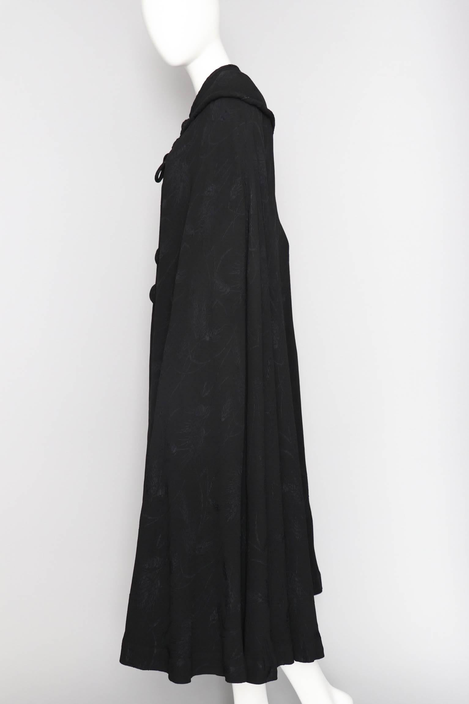 An absolutely incredible handmade 1930s long black silk opera cape with beautiful jacquard woven ears of wheat. The cape is fitted around the shoulders and can be tied at the front. The cape is fully lined with white silk. 

