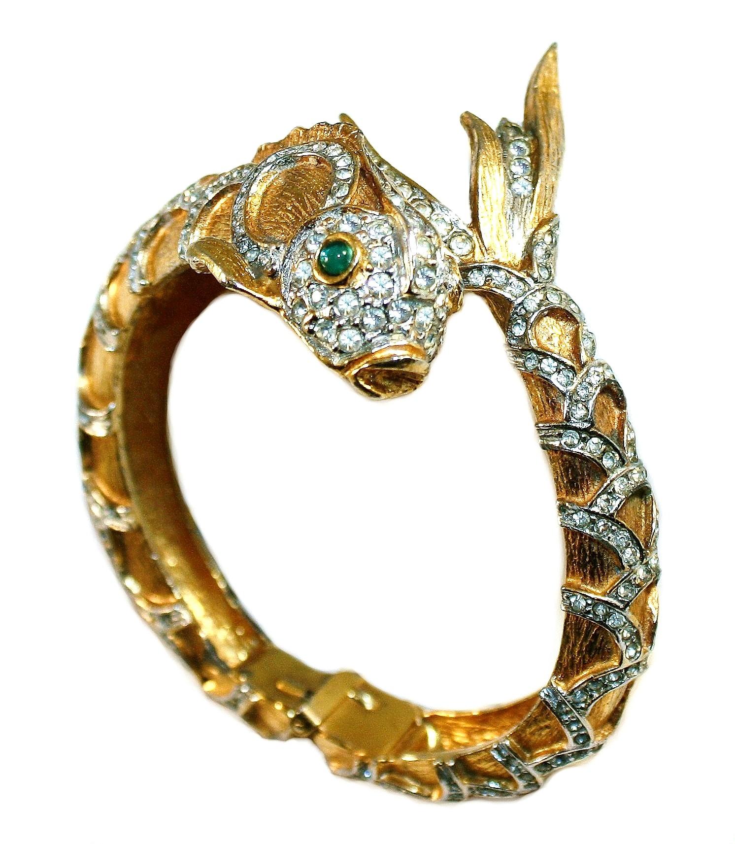 Circa 1970s Kenneth Lane bright, gold tone textured metal hinged bangle made in a Koi fish design.  It is set with small clear crystals and green glass cabochon eyes.  The interior measures 6.5
