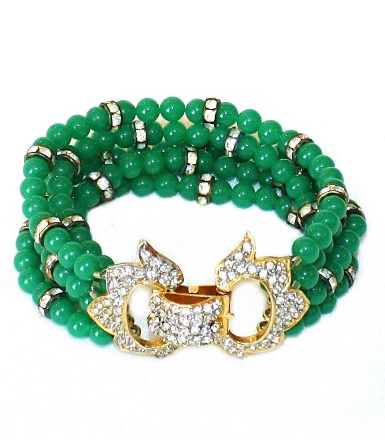 Circa 1960s K.J.L., Kenneth J. Lane, multi-strand green glass bead bracelet spaced with rhinestone roundels.  It fastens on top of the wrist with a gold-plated metal clasp, set with clear faceted crystal stones.  The bracelet measures 8