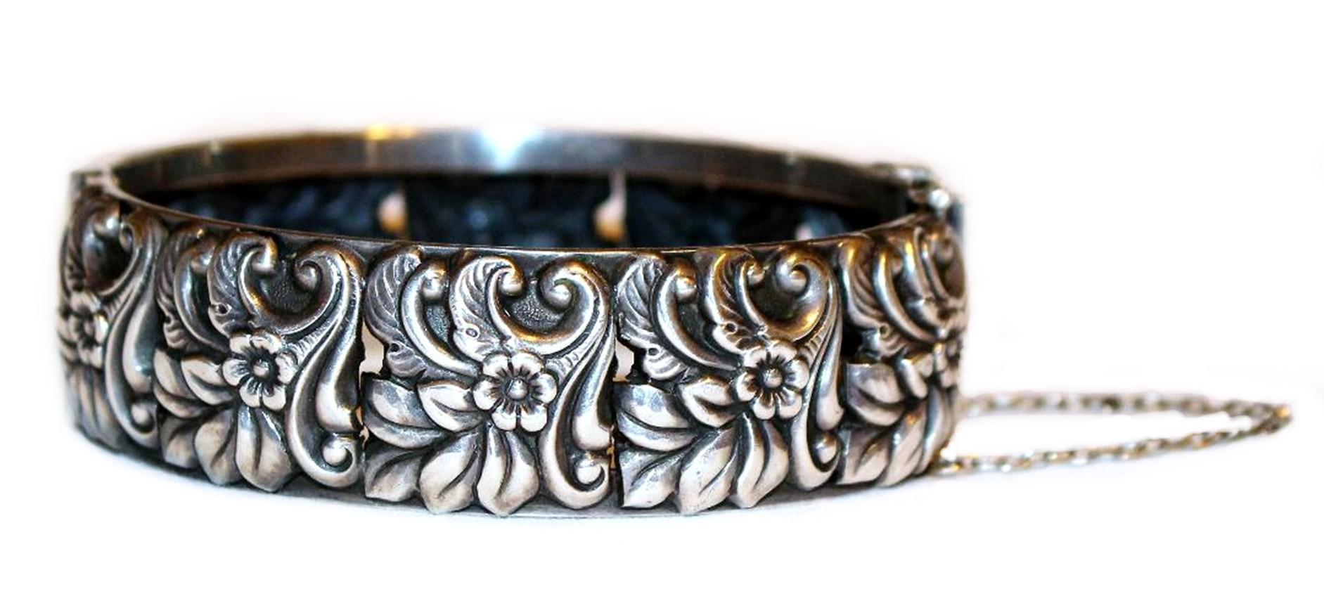 Hallmarked sterling silver hinged bangle with a repoussé floral motif all around the exterior. The interior measures 7.25