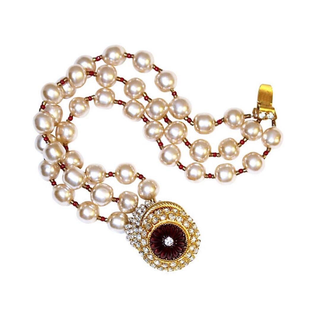 Circa 1960s William deLillo faux-pearl, multi-strand bracelet with small glass bead spacers and a jeweled clasp.  The clasp is worn on the top of the wrist and set with a red molded glass center embellished with small faux-pears and prong-set