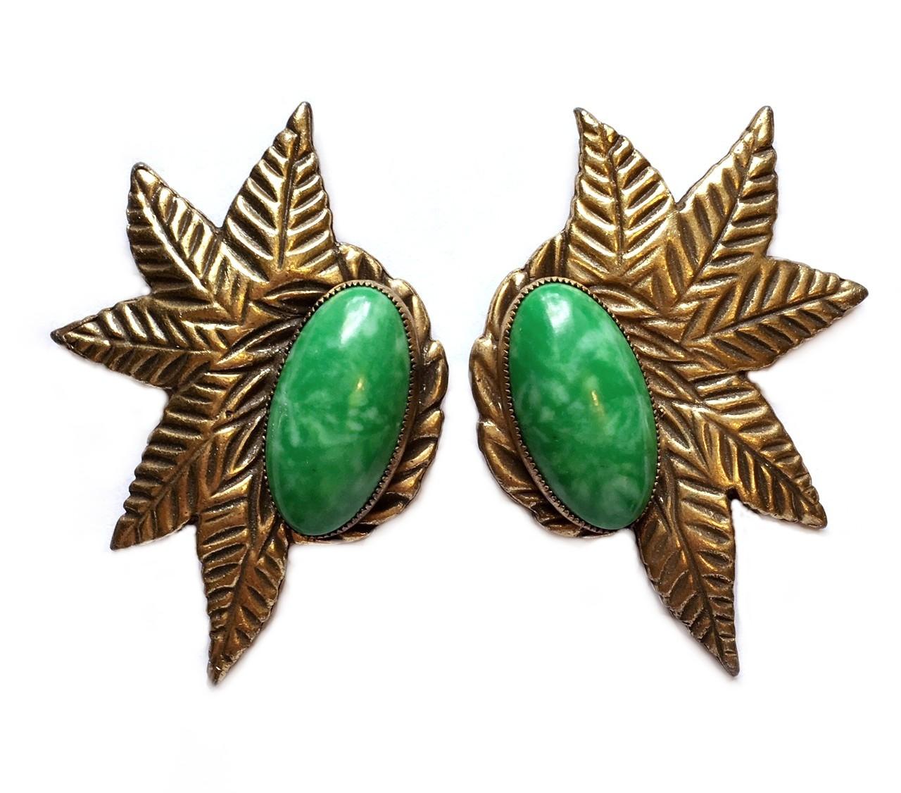 Circa 1930s gold tone metal dress clip pair in a stylized leaf design with bezel set, large oval green glass cabochons.  This Deco era pair are heavy, well made and very versatile accessories.  Each clip measures 3