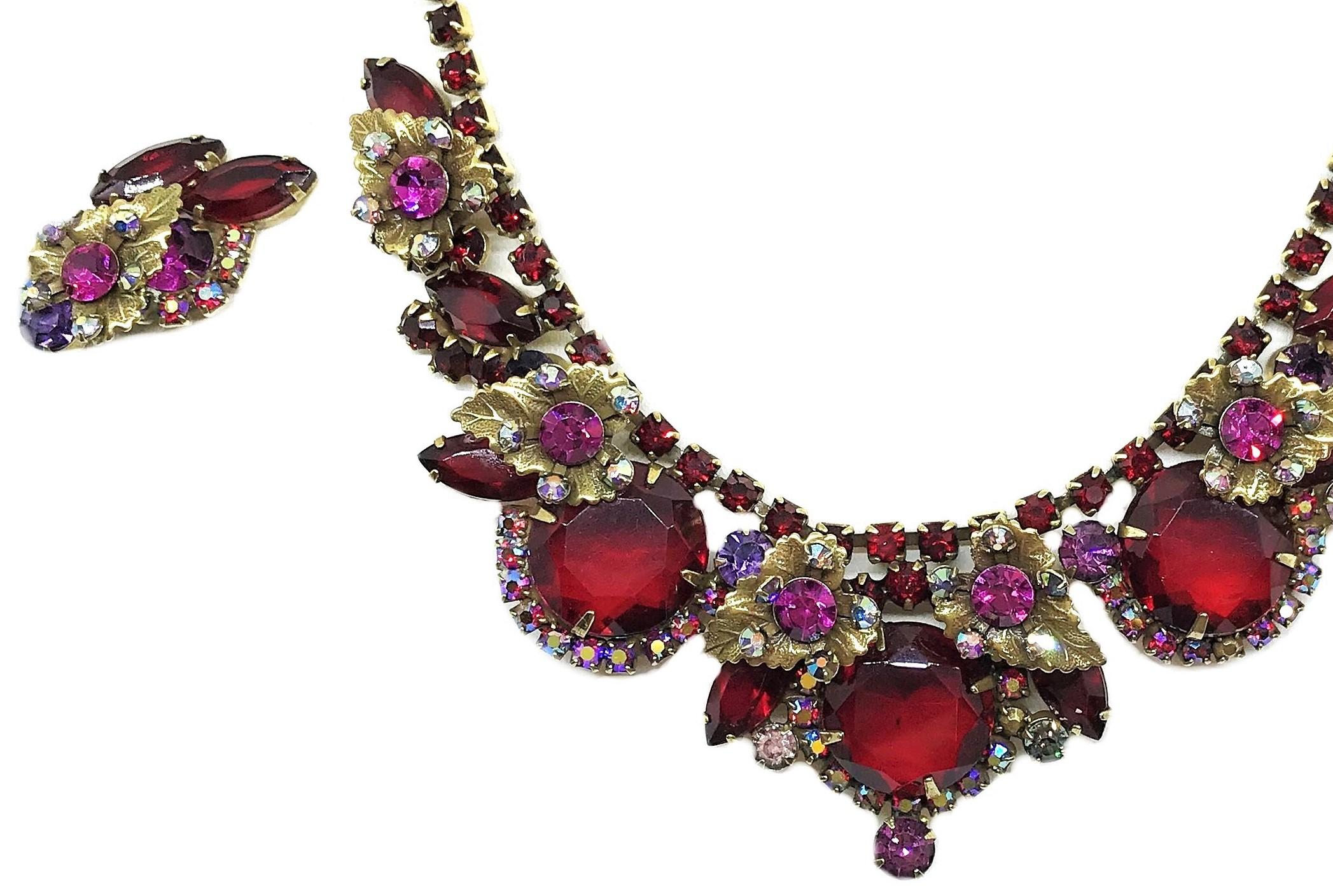 Circa 1960s Juliana necklace and earring set by De Lizza and Elster of New York.  The gold tone metal necklace and clip back earrings are prong set with large red faceted glass round and marquis stones, and embellished with gold leaves, bright pink