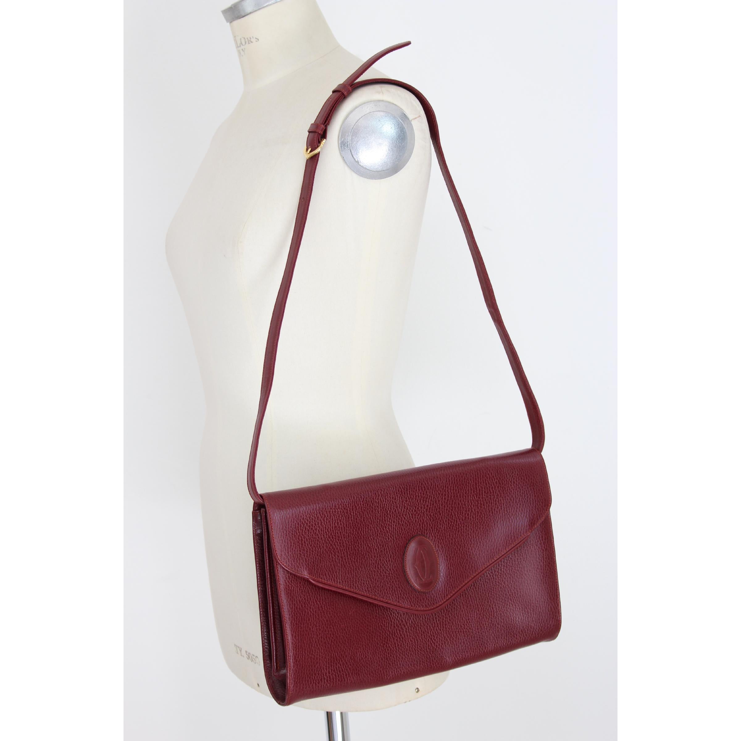 Must De Cartier women's vintage shoulder bag, burgundy color 100% textured leather. Internal dividers, removable shoulder strap. Excellent vintage conditions. Made in Italy.

Width: 32 cm
Length: 22 cm
Depth: 5 cm