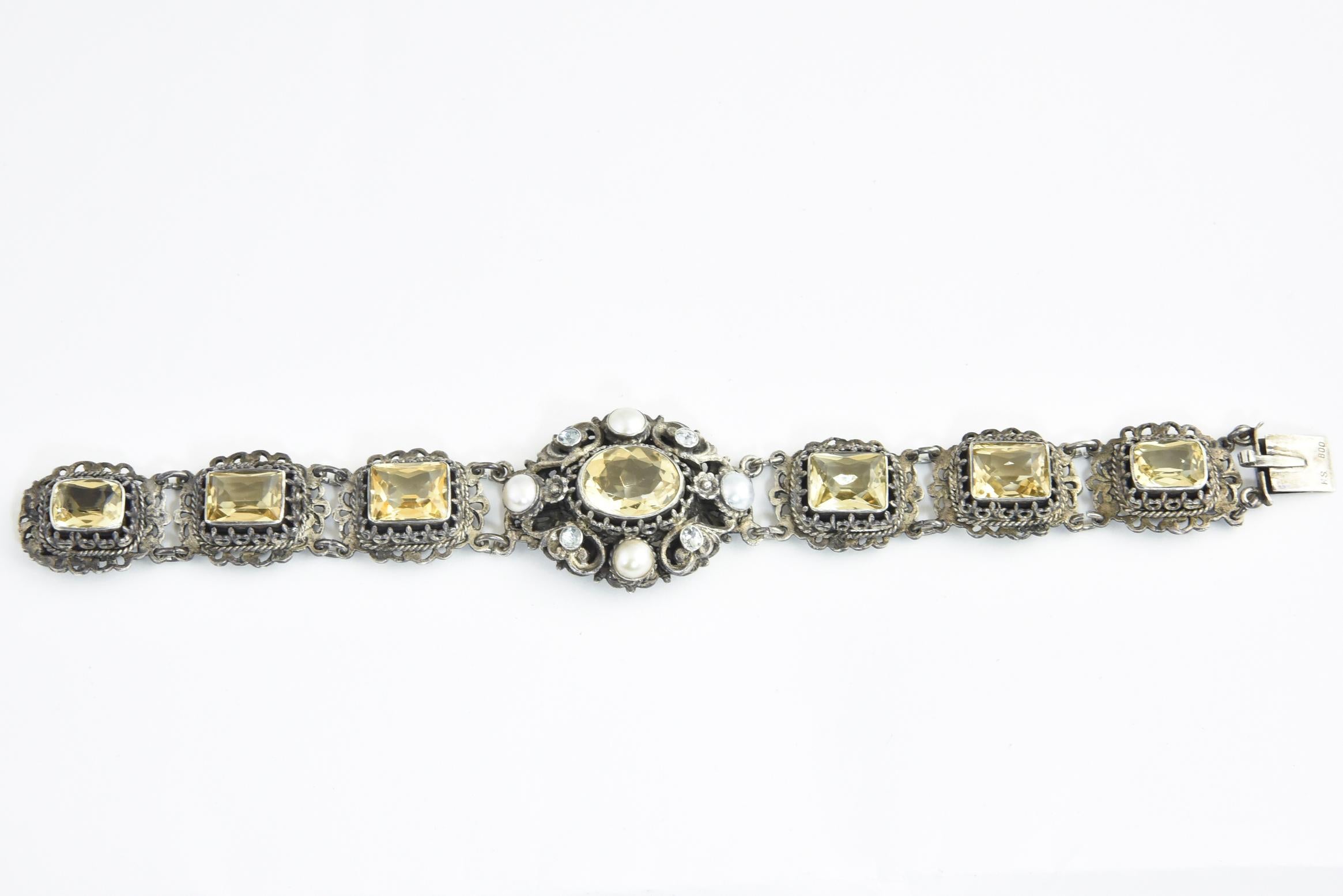 Österreichisch-ungarischer Citrin-Armreif, entstanden zwischen 1860 und 1910. Ein ovaler Citrin, umgeben von einem verzierten Silberrahmen mit Perlen- und Pastenakzenten. Der Hauptteil besteht aus einem Band mit 6 Zitrinen, die in silberne Rahmen