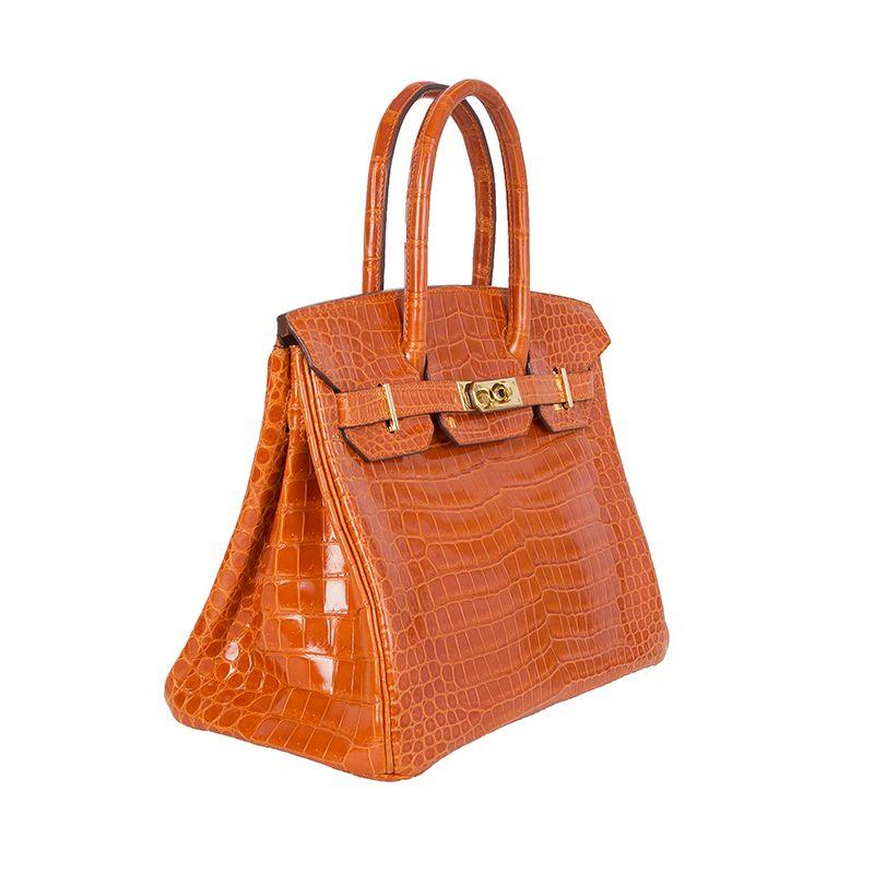 Hermes 'Birkin 30' in orange shiny Porosus crocodile. Lined in Chevre (goat skin) with an open pocket against the front and a zipper pocket against the back. Has been carried and is in virtually new condition. Comes with keys, lock, clochette, dust