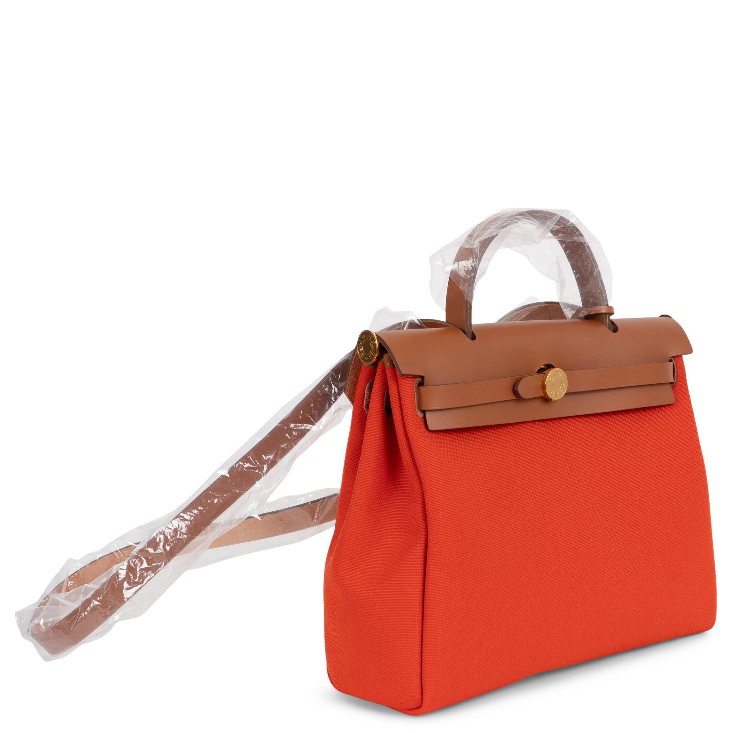 Questa borsa Hermès Zip 31 Retourné, autentica al 100%, è realizzata in tela Mécano Toile Militaire arancione con finiture in pelle Fauve Vache Hunter e finiture dorate. La silhouette strutturata presenta una chiusura con fibbia firmata Clou de