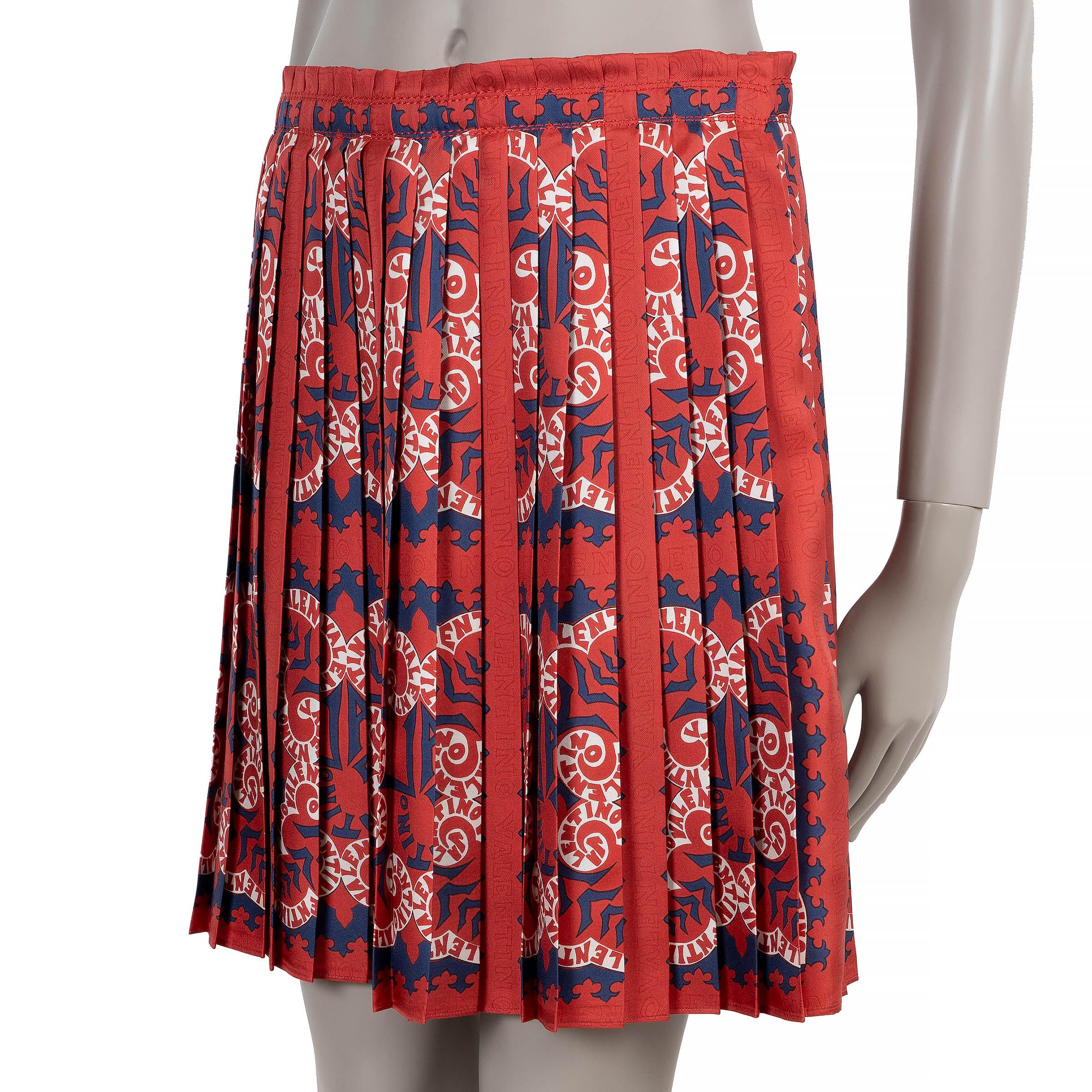 Cette jupe plissée 100% authentique Valentino est confectionnée en soie rouge avec un imprimé Bandana Logo bleu marine et blanc. Elle présente une silhouette en ligne A avec une longueur mini flatteuse et des plis souples pour un mouvement élégant.