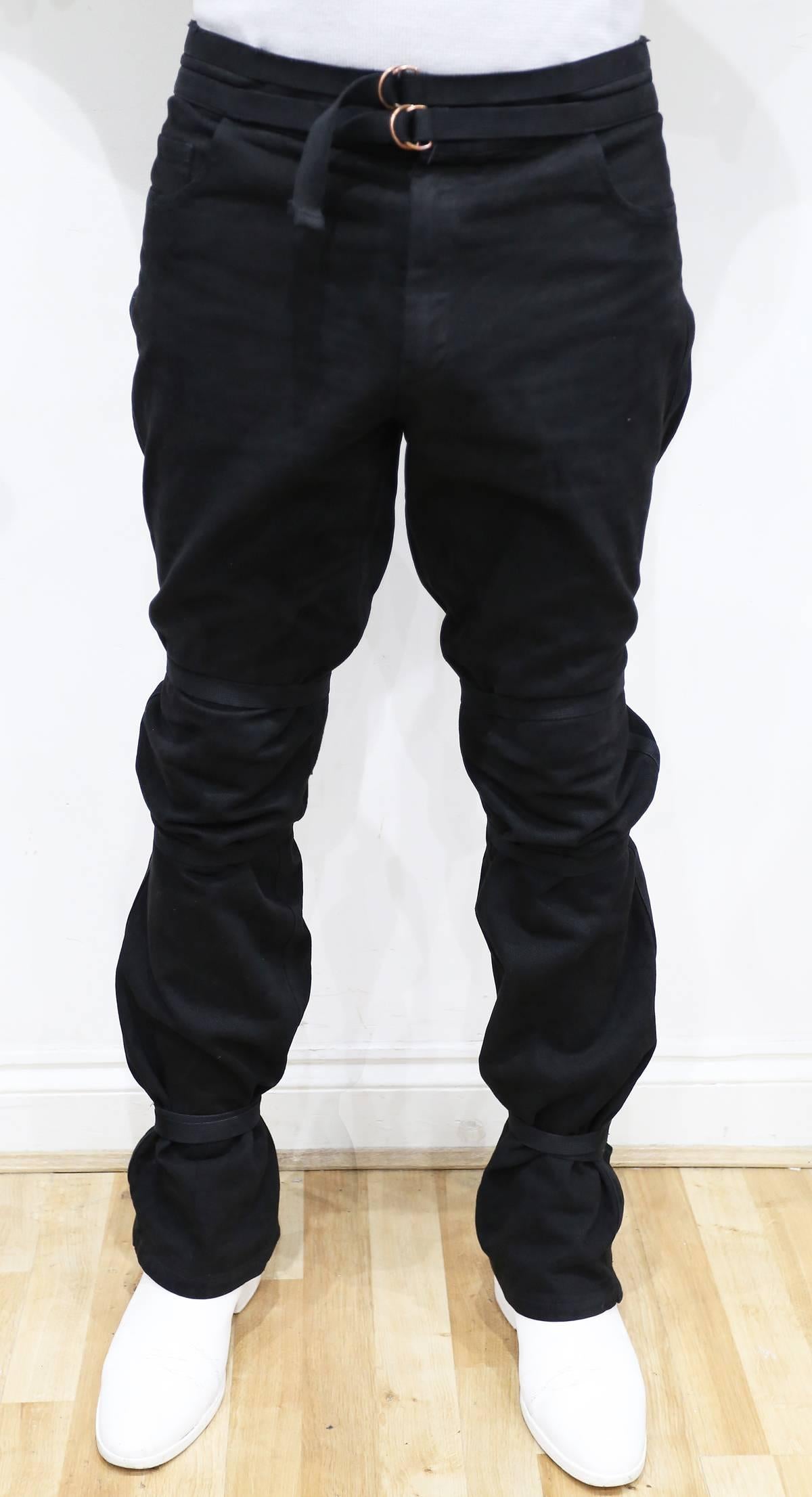 Ultra rare and highly collectable Raf Simons bondage jean pants from the Spring-Summer 2003 'CONSUMED' collection. The black jeans feature three bondage straps on each leg and can be style in various ways. 

Mens Size: 52