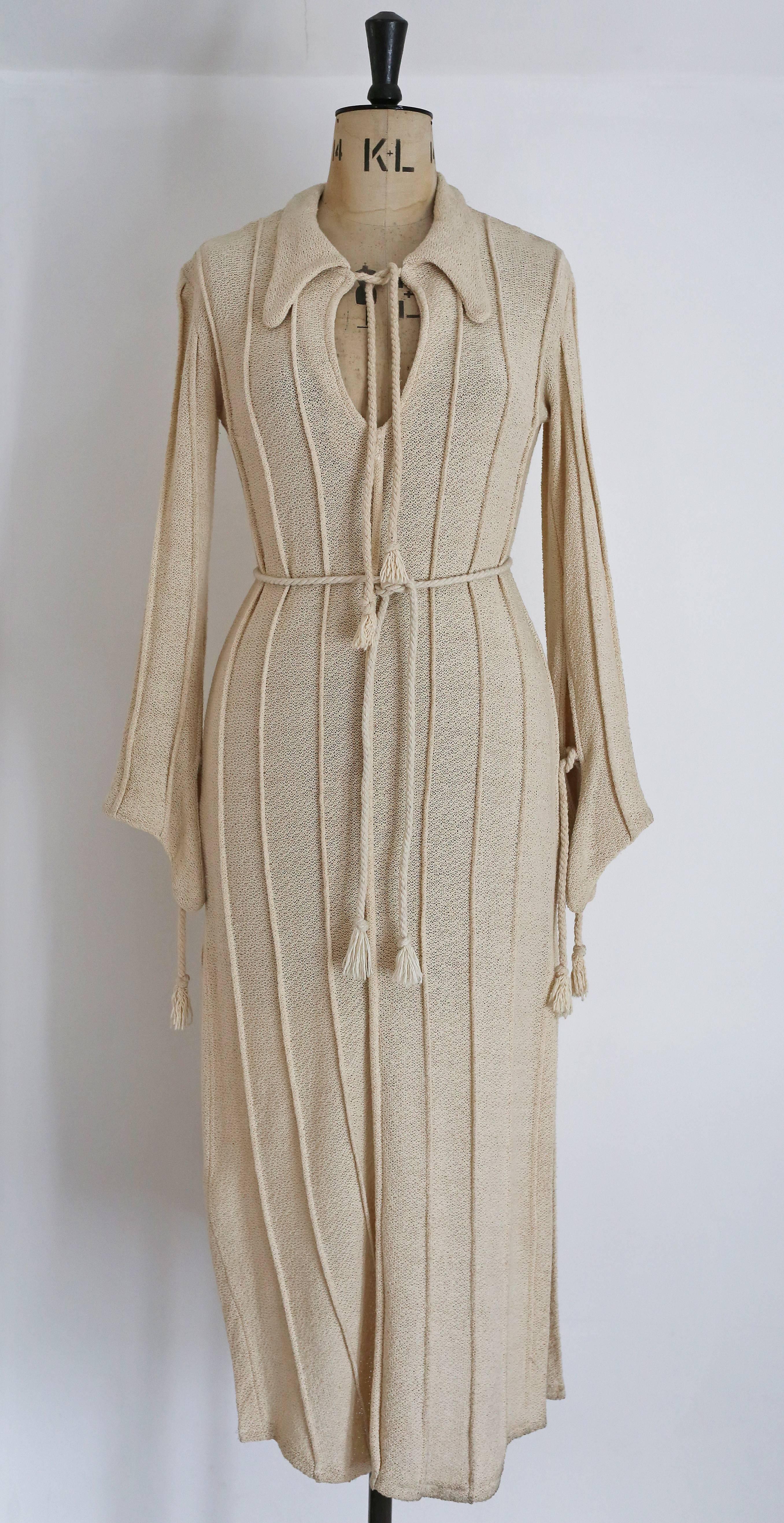Ivory knitted caftan by Alexander Campbell, circa 1990s. The caftan features several ties with tassels, high side slits and dog ear collar. 

Size: Medium
Shoulder to shoulder -18