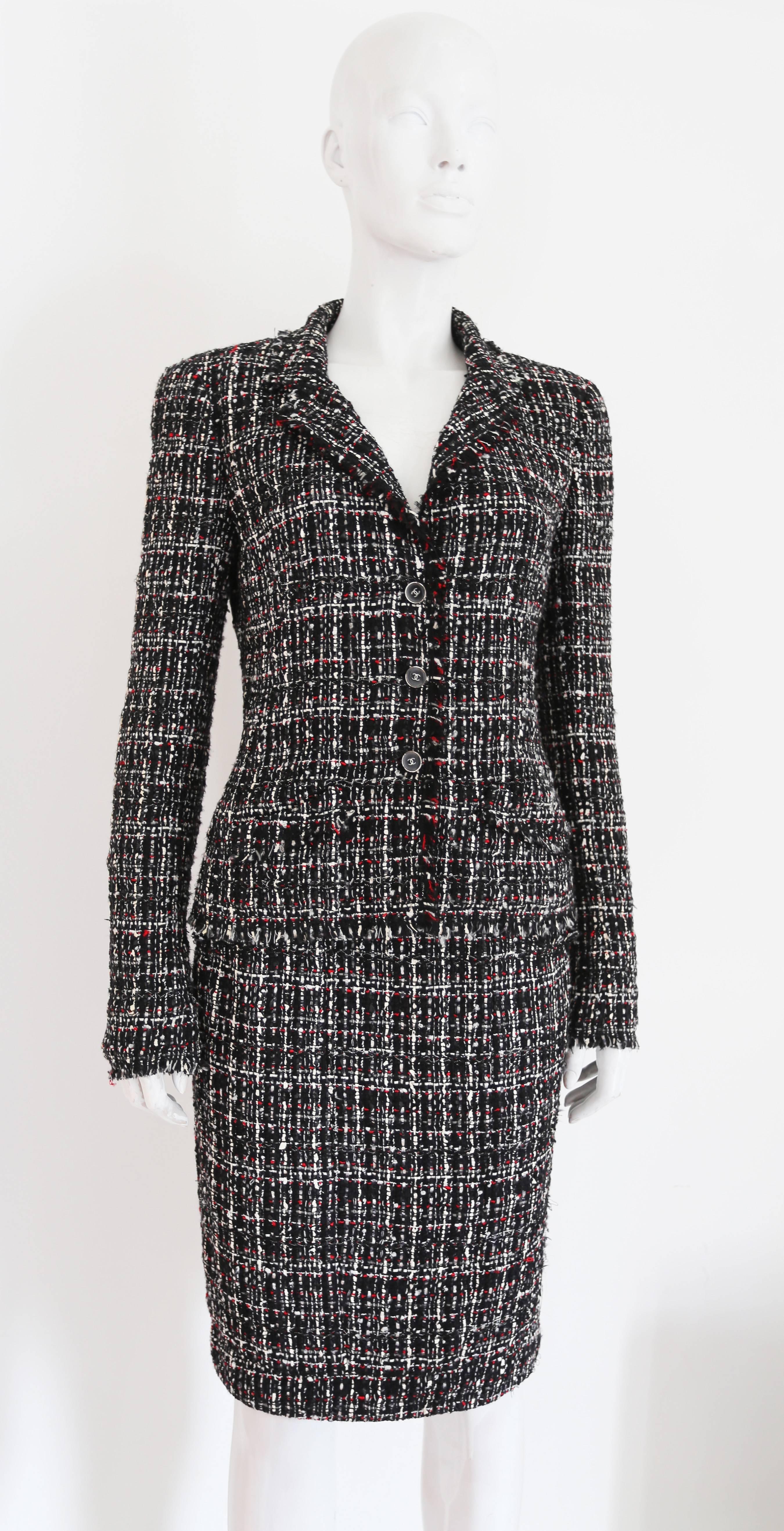 Chanel tweed skirt suit, circa 2005. The suit includes a tailored jacket with frayed trim, silk chiffon lining and CC logo buttons throughout and a fitted pencil skirt with two hidden front pockets.  The tweed consists of woven red, black and white