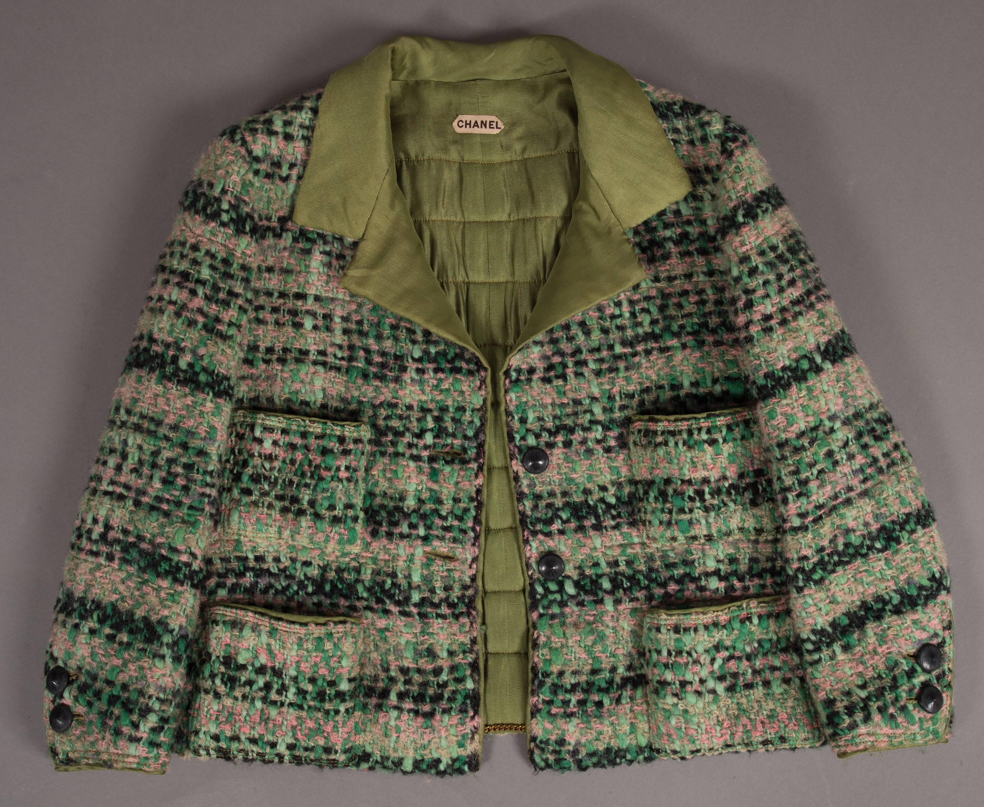 A Chanel haute couture tweed skirt suit, circa 1960s. Baby-pink, black, mint and green coloured tweed, olive green quilted silk interior, chain trimmed hem on jacket, four open pockets and black button closures throughout. 