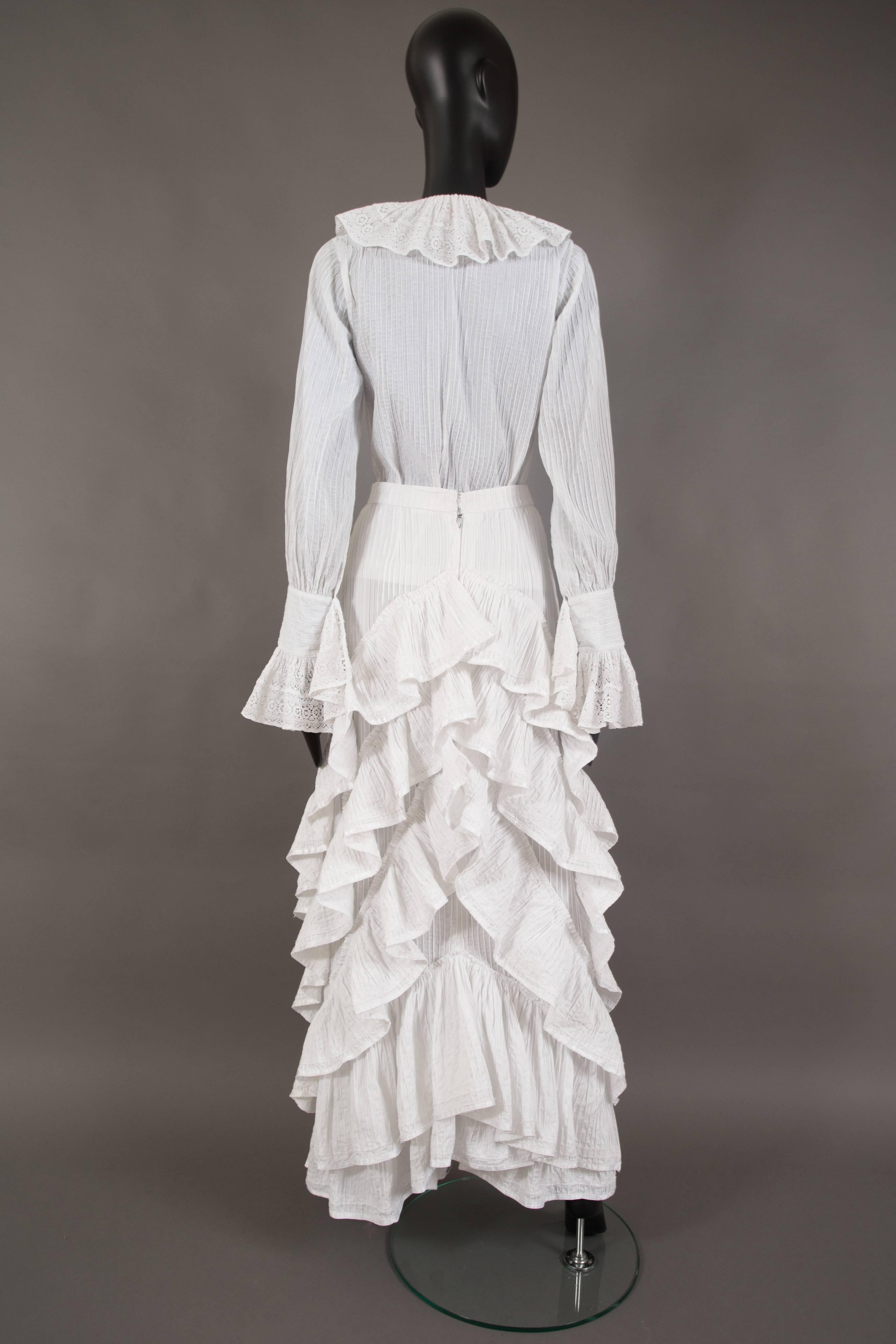 A rare Mexicana white pintucked cotton skirt suit, circa 1960. 

Bishop sleeved blouse with lace cotton frills on cuff and collar. High waisted full skirt with ruffled back and metal zip closure at rear. 

Mexicana was a London boutique on Lower