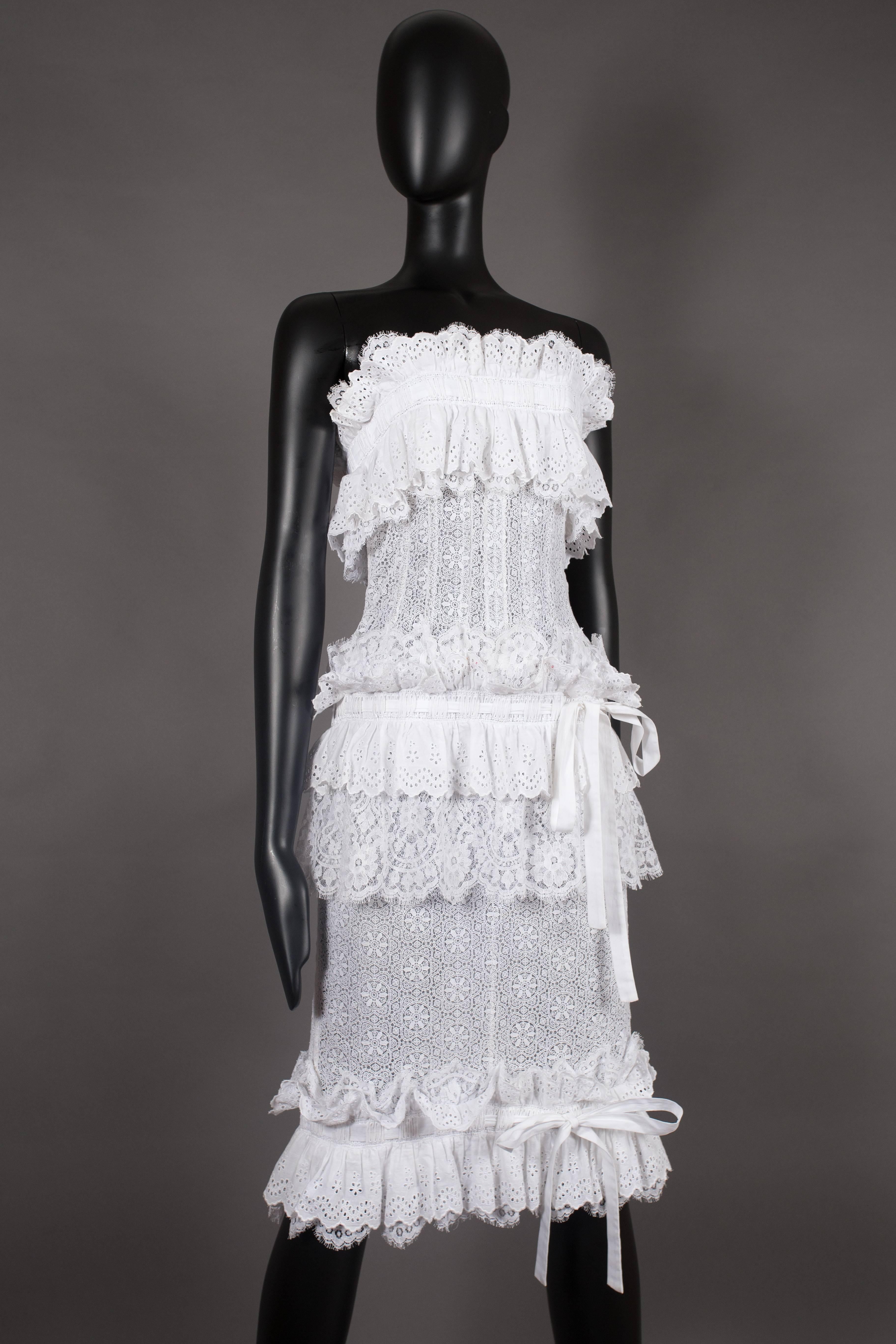 A Dolce & Gabbana couture strapless white dress, spring-summer 2006. Heritage lace, hand clipped french lace, broderie Anglaise lace, boned corset bodice, three cotton bow ties, metal zipper closure and high slit at rear centre seam. 
